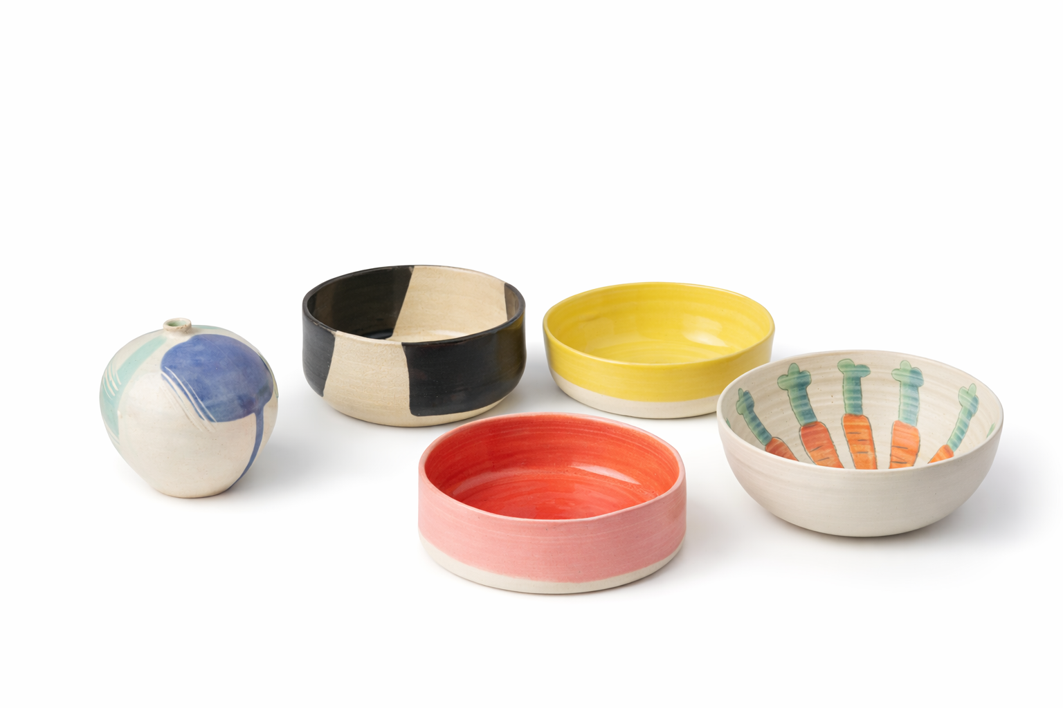 Cinq bols en céramique colorés et décorés disposés sur un fond blanc.