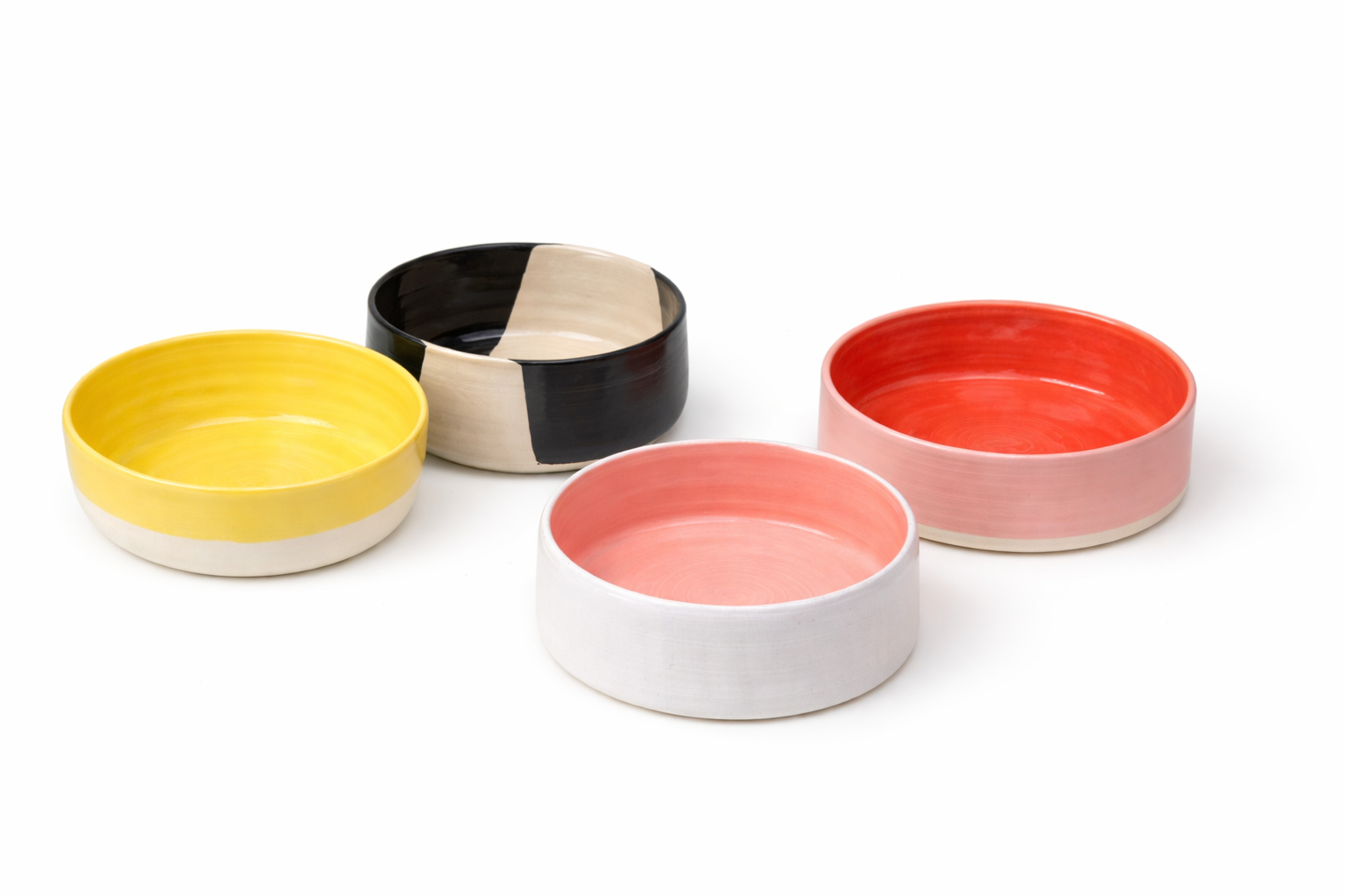 Cinq bols en céramique de différentes couleurs et motifs, disposés sur un fond blanc.