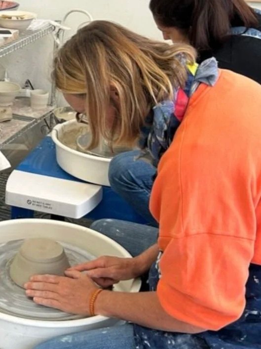 Deux femmes travaillent sur un tour de potier, façonnant de la poterie en argile dans un atelier de céramique.