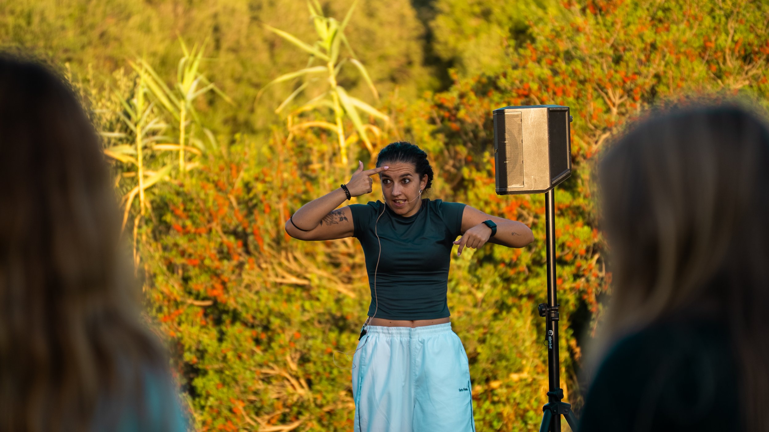 A group of people holding hands in a circle while standing in water during sunset.