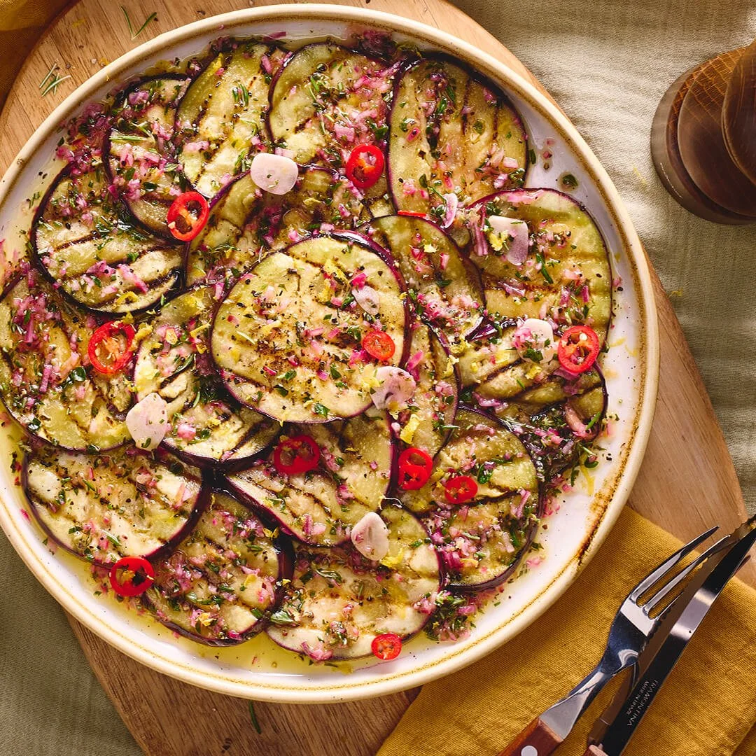 Een bord met gegrilde plakken aubergine met italiaanse kruiden