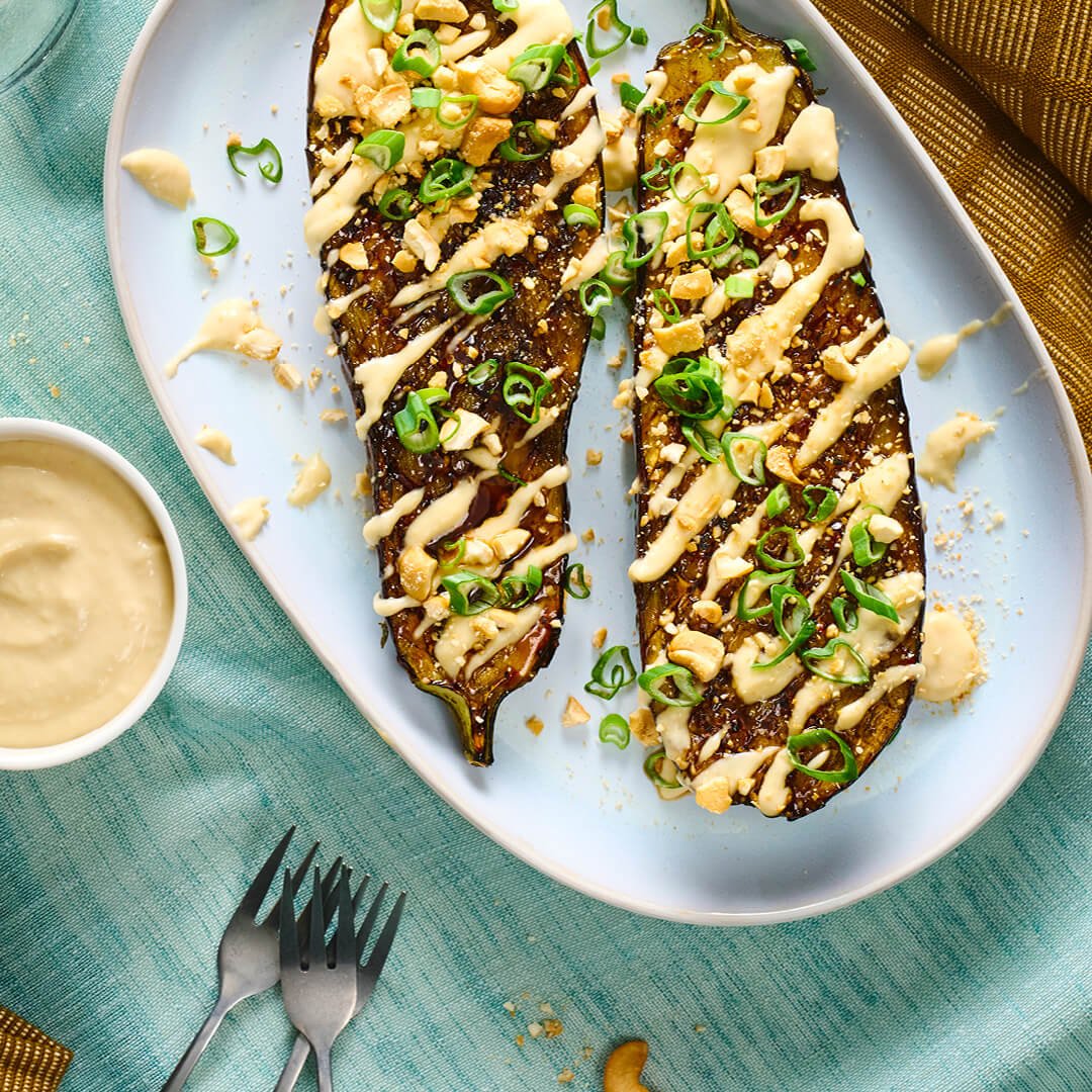 Bord met gehalveerde gegrilde aubergine met toppings en een Teriyaki glaze 