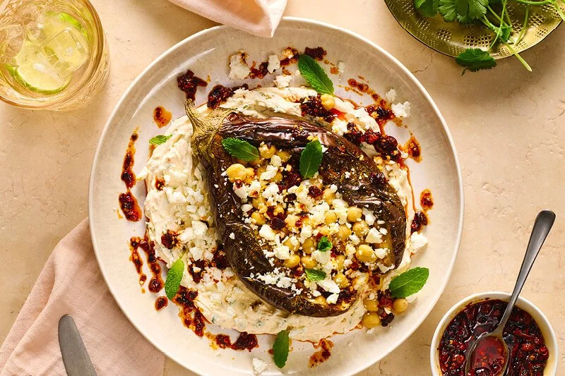 bord met gepofte aubergine geserveerd met kruidige Turkse yoghurt en crispy chili oil