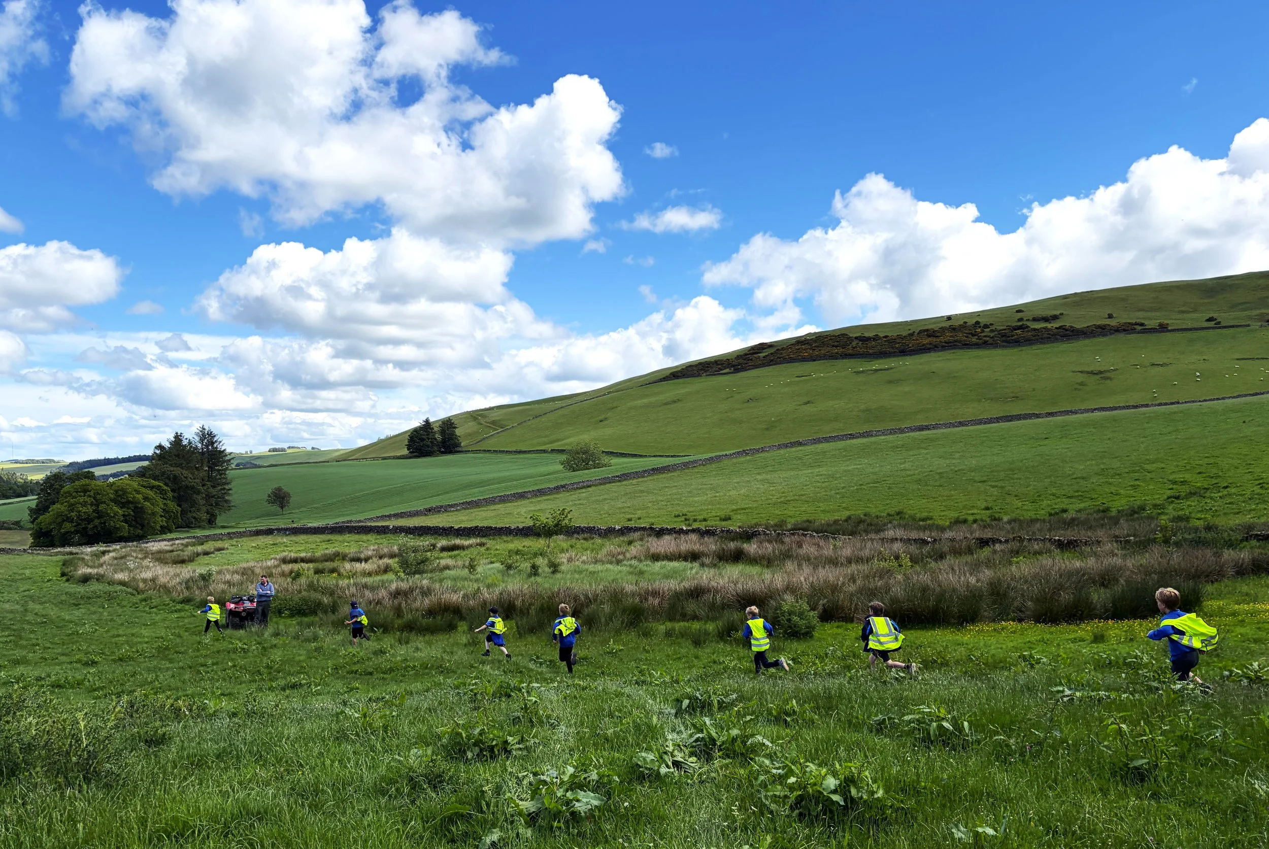 A line of school pupils walk down a field.