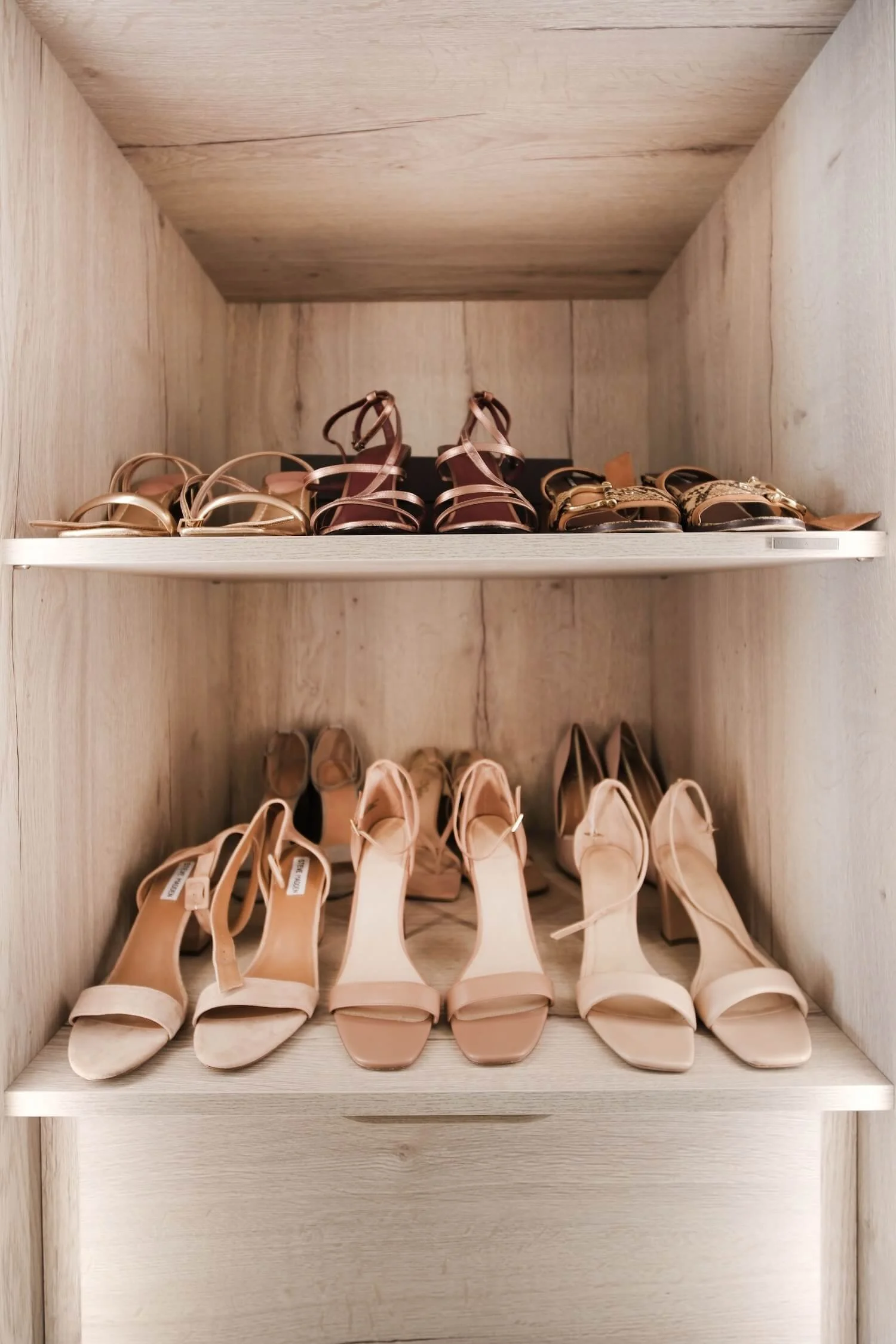 High healed shoes and women's sandals arranged neatly on shelves in a dressing room. 