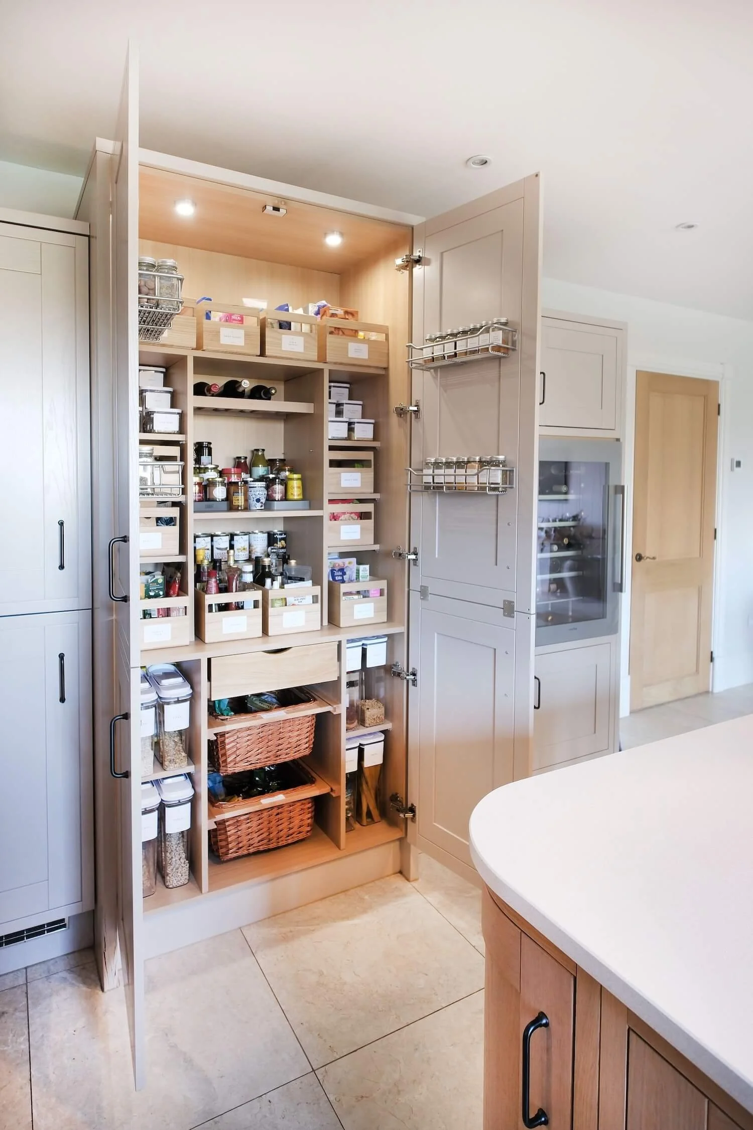 An organised pantry showing food decanted in dispensers, food organised in wooden sustainable boxes, and bespoke labels.
