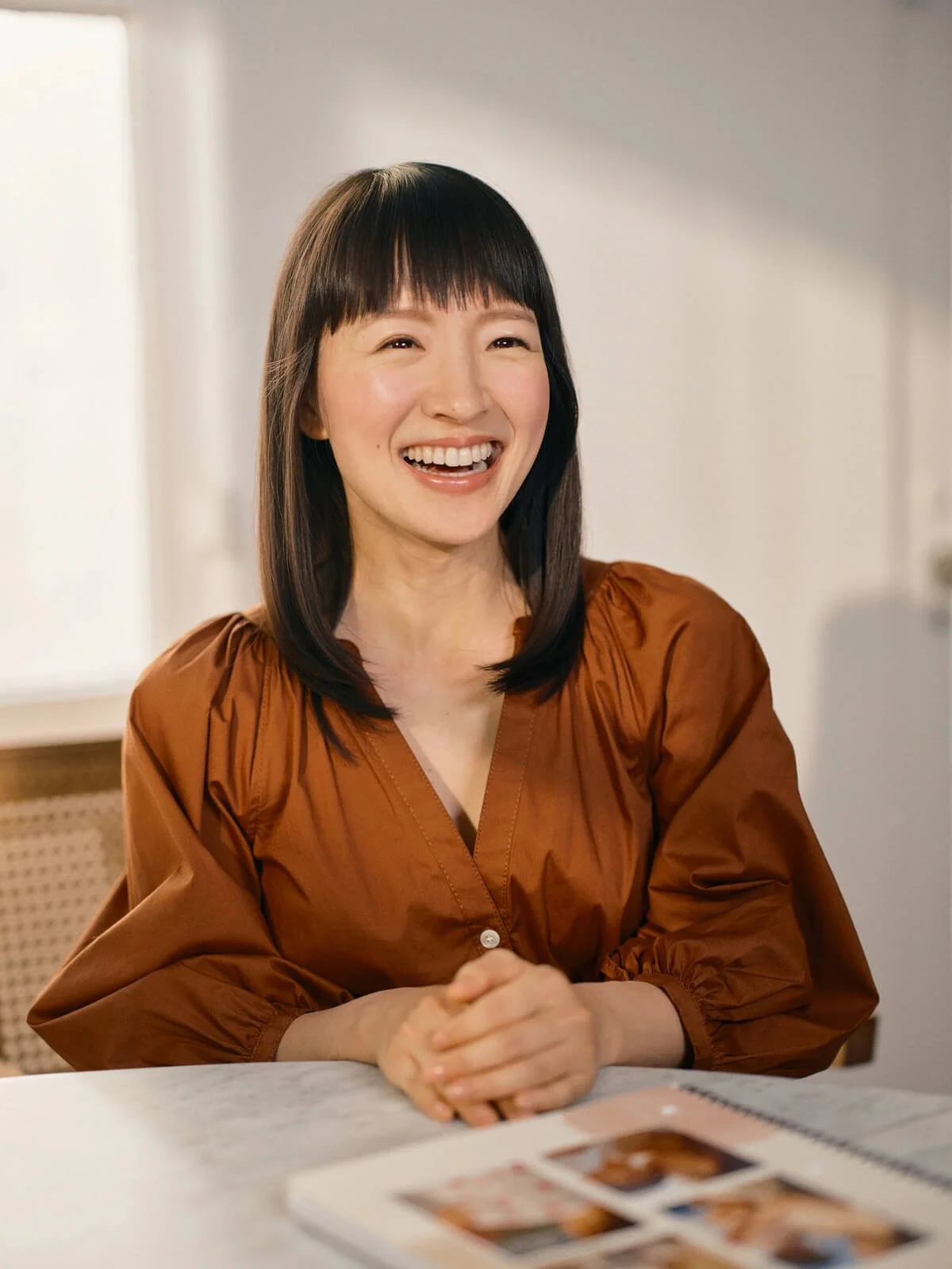 Marie Kondo smiling wearing a brown shirt.