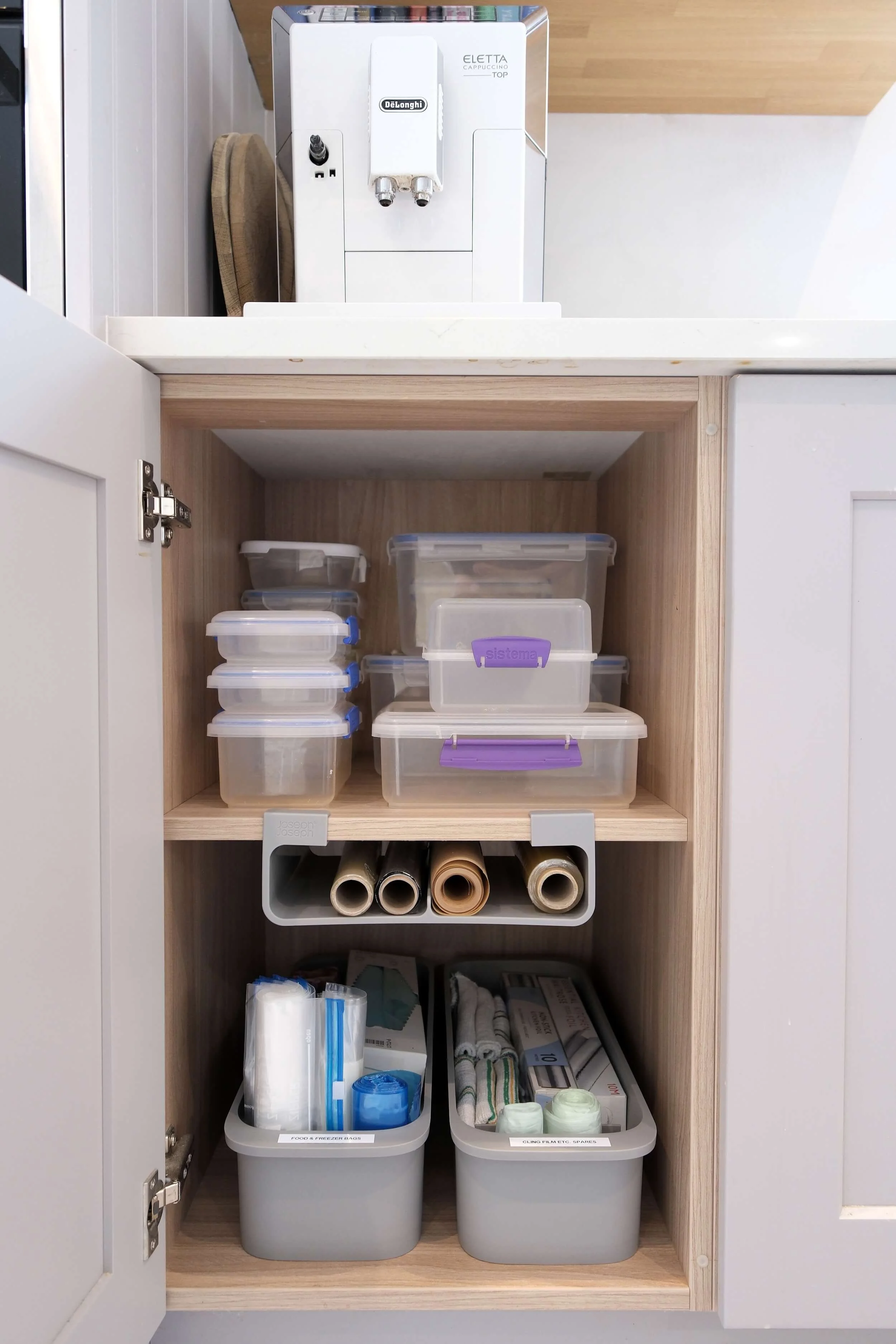Open cabinet with plastic storage containers, cardboard tubes, and emergency supplies inside.