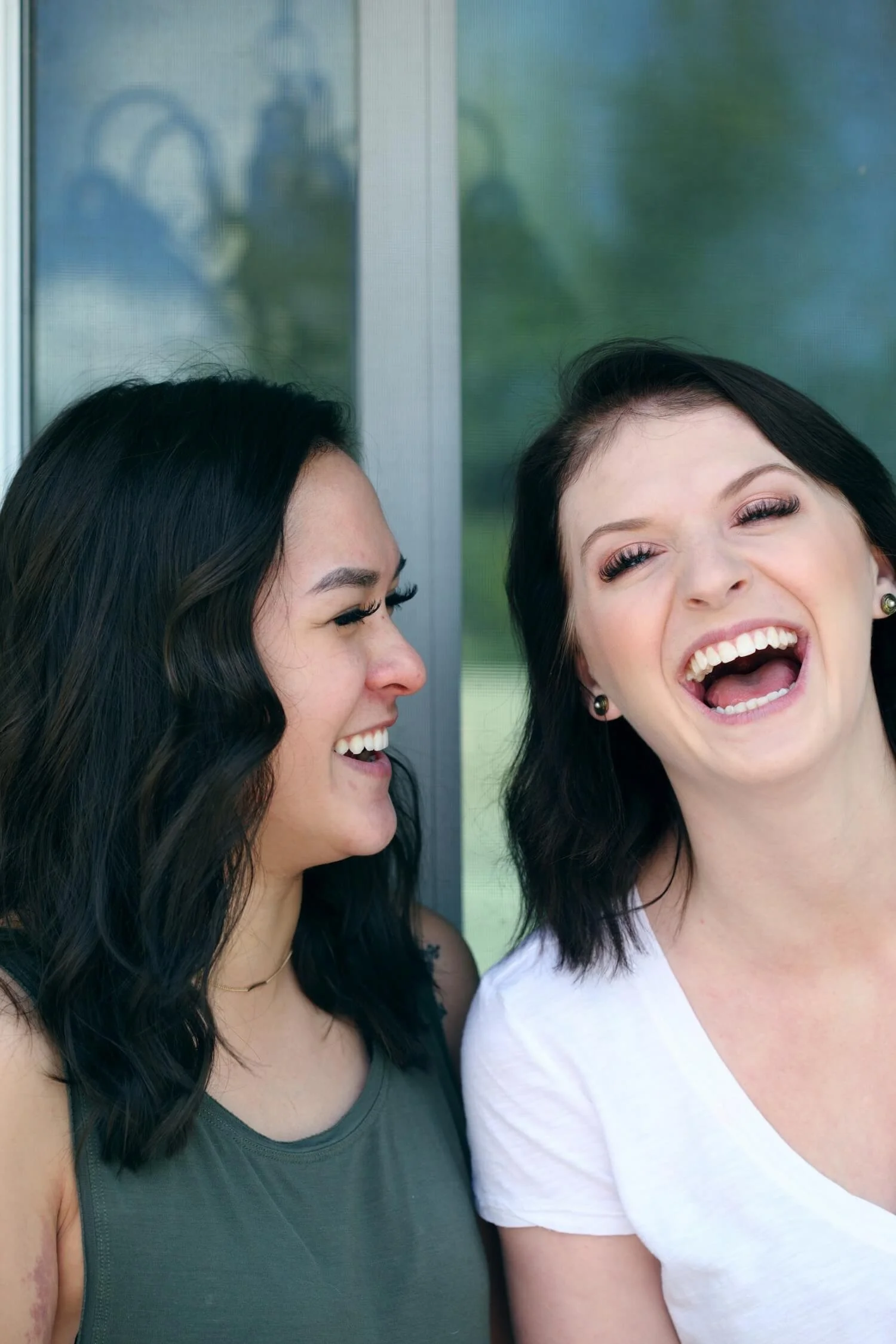 Two women looking at each other and laughing, looking happy.