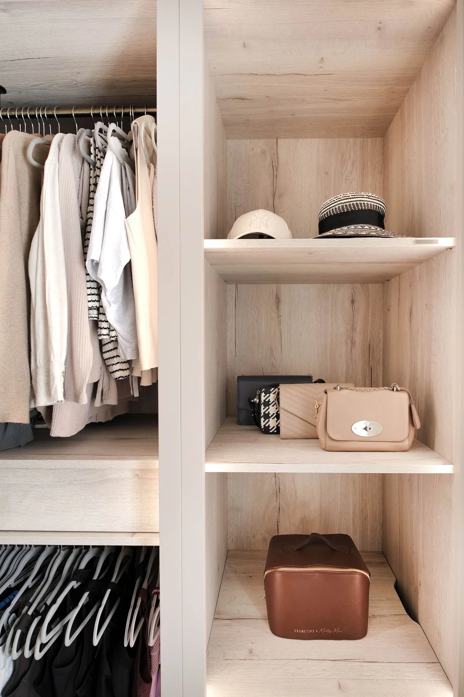 Organised shelf in a dressing room showing luxury branded handbags and hats, with hanging garments neatly organised. 