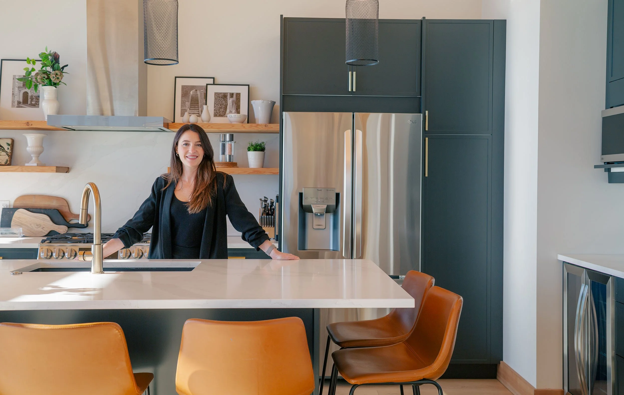 Jessica Bertrand, RE/MAX Invermere real estate agent, standing in a modern kitchen and smiling toward the camera. The scene introduces her services for buyers exploring homes for sale in Invermere, BC.
