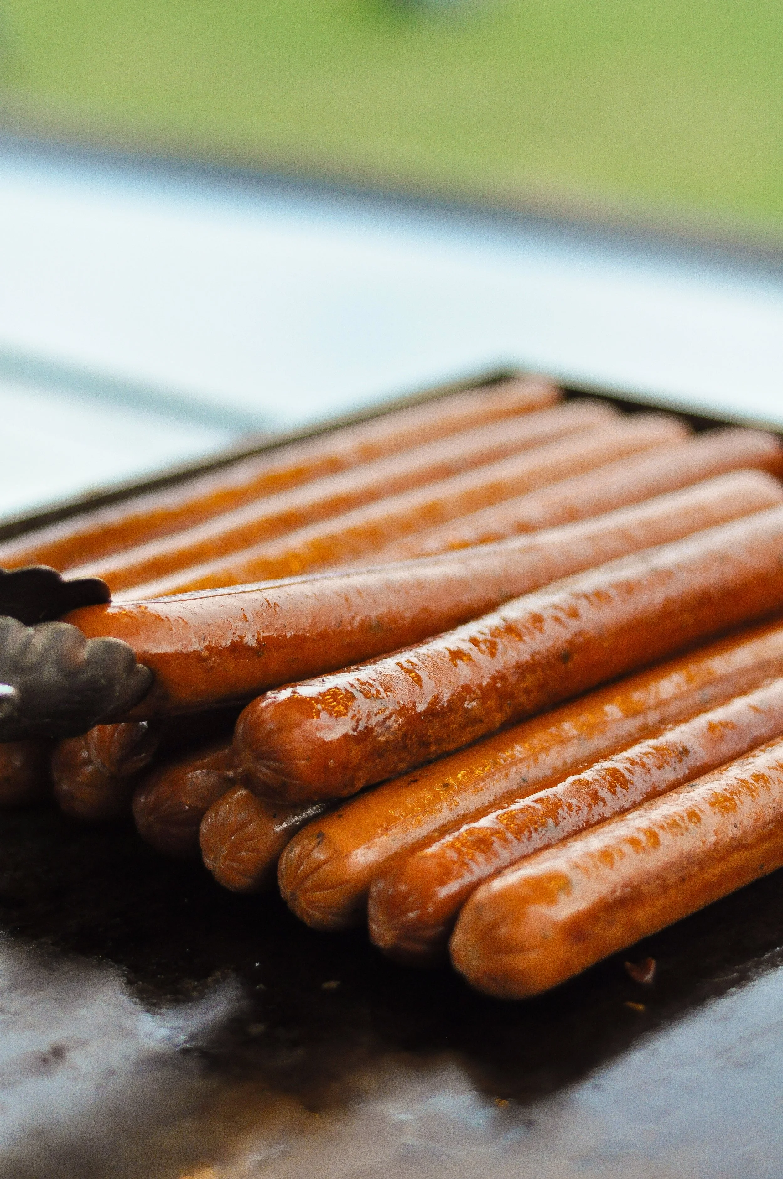 Close-up of hot dogs on a grill, glazed and ready to eat.