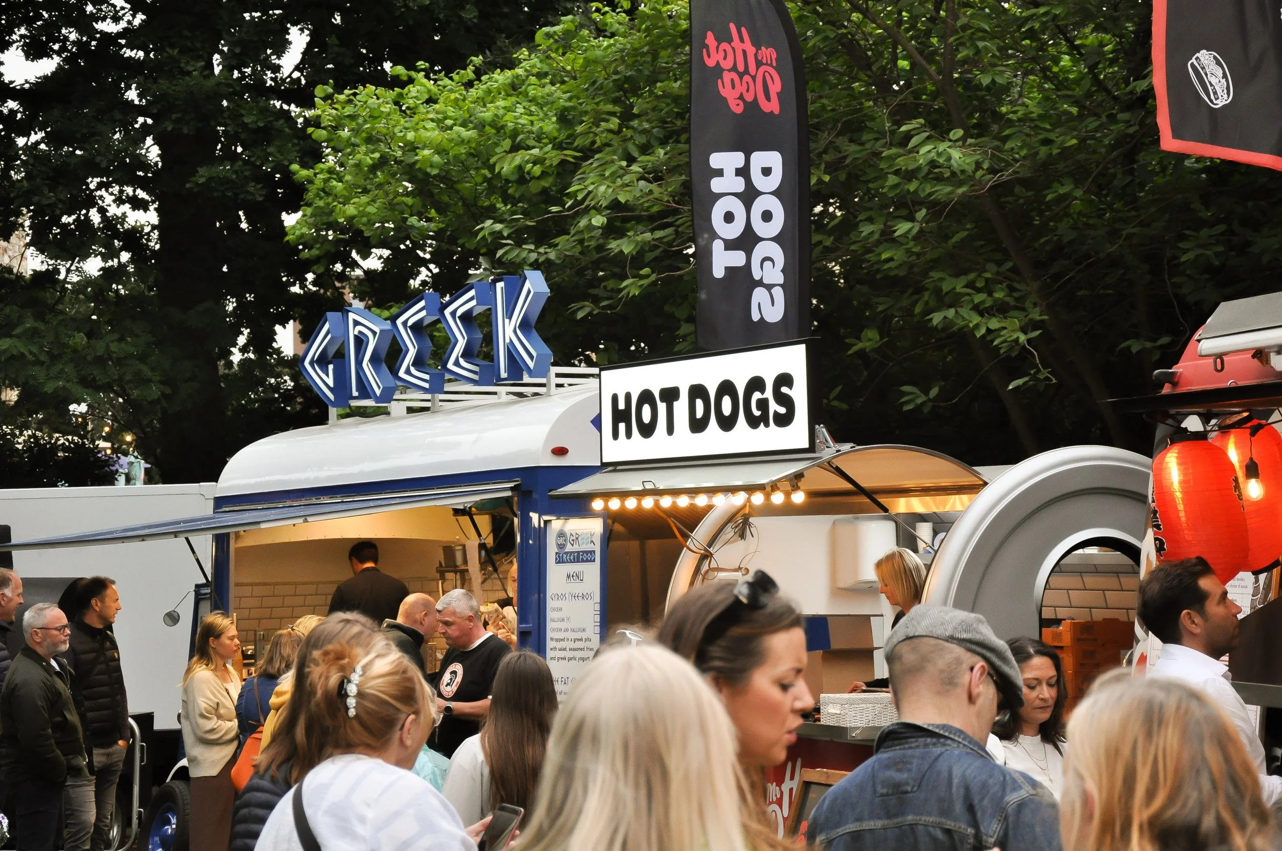Mr Hot Dog Food van at a festival with a crowd of people and and lit up sign that reads hot dogs