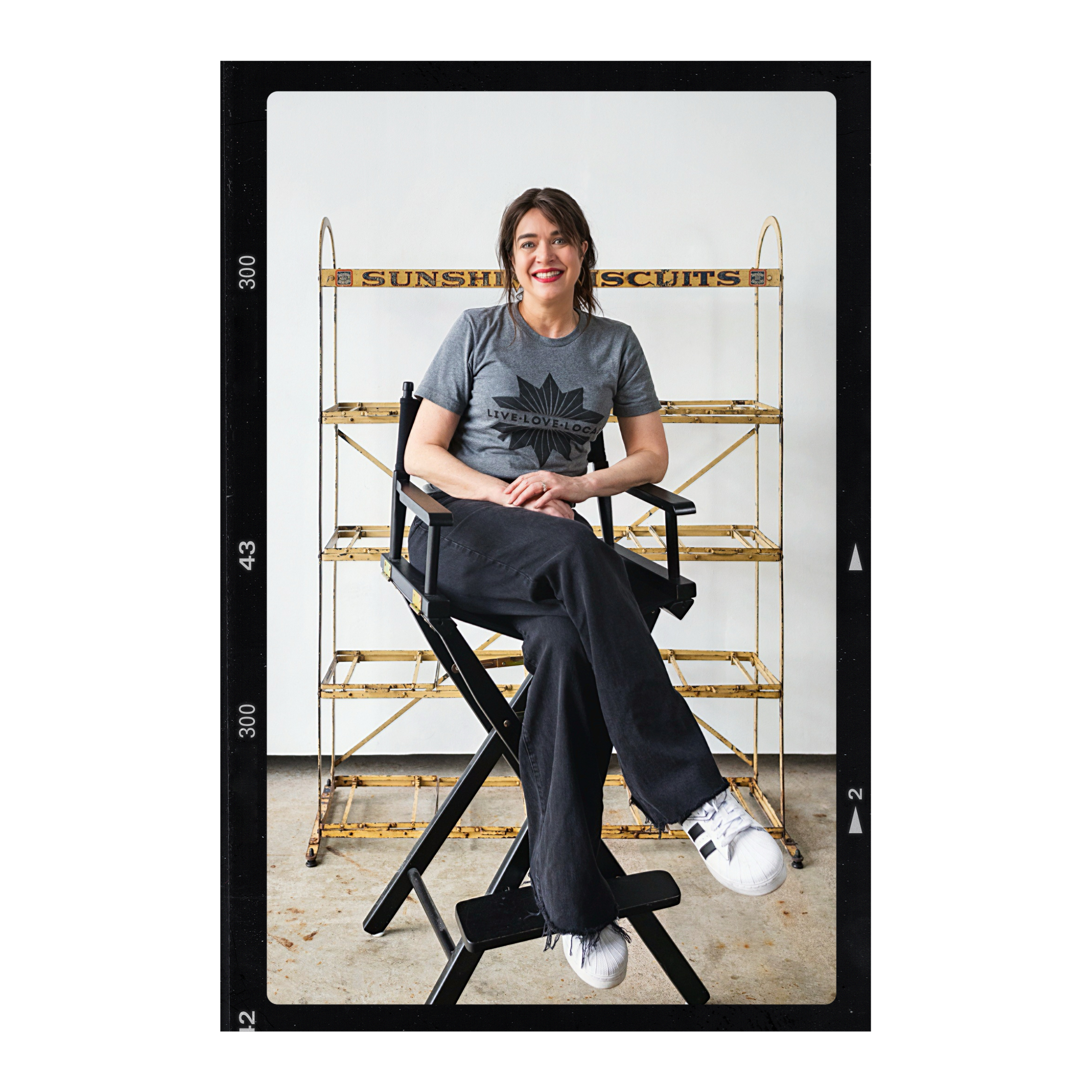 Kathleen "Katalina" Day sitting in a directors chair in front of a vintage shelf.