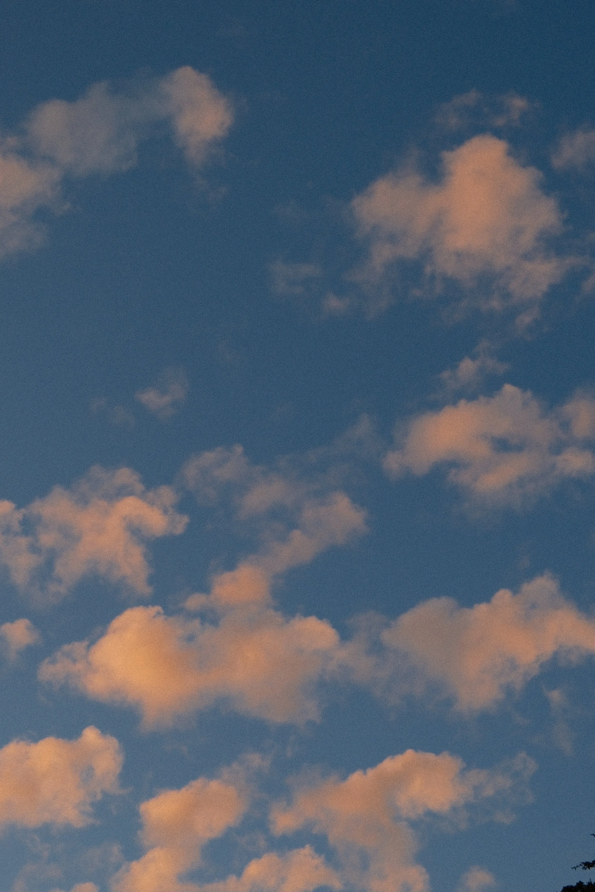 Sky with scattered clouds, some illuminated with a soft pinkish-orange hue.