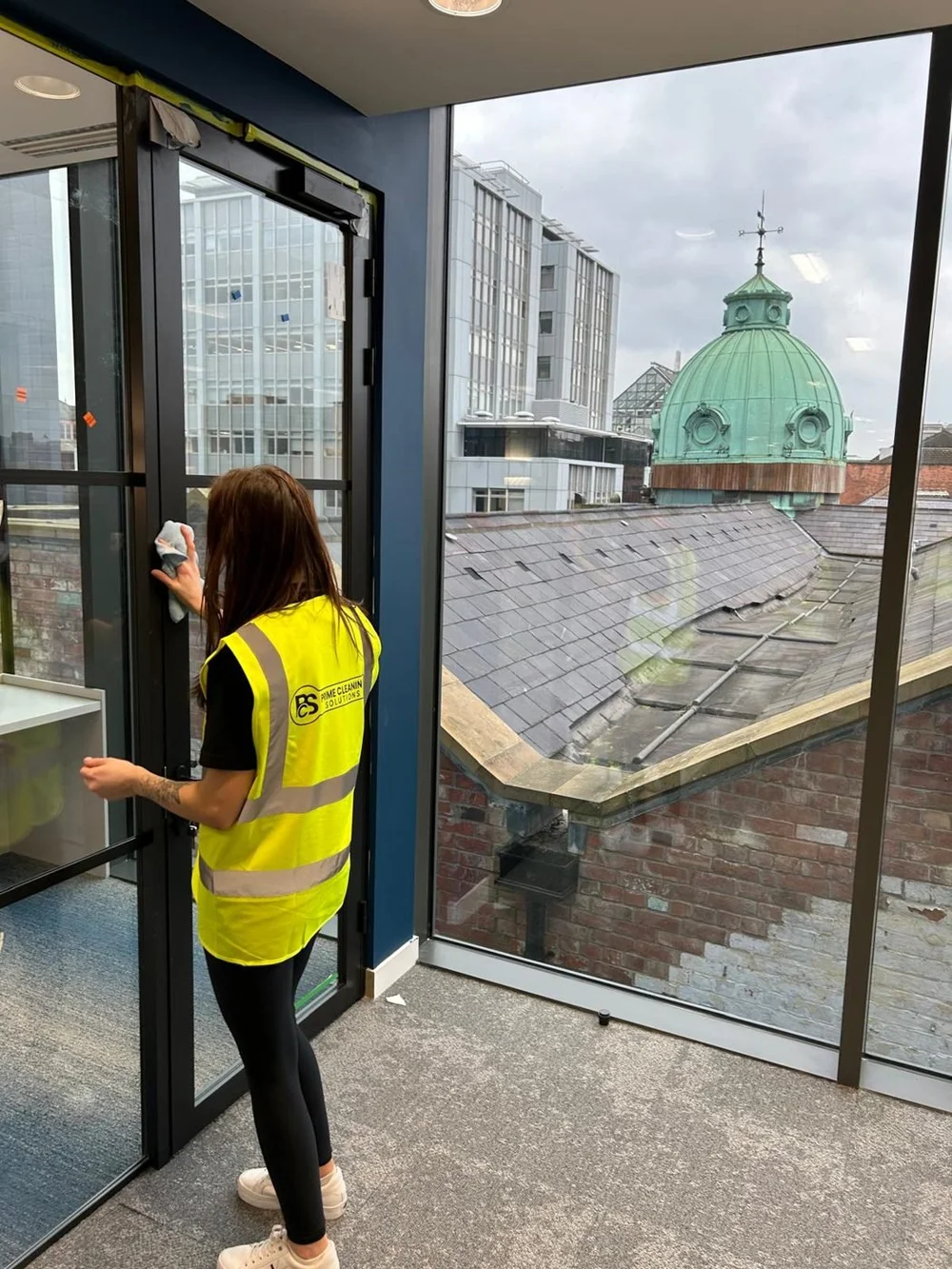 Prime Cleaning Solutions cleaner wiping glass in a Belfast city centre office