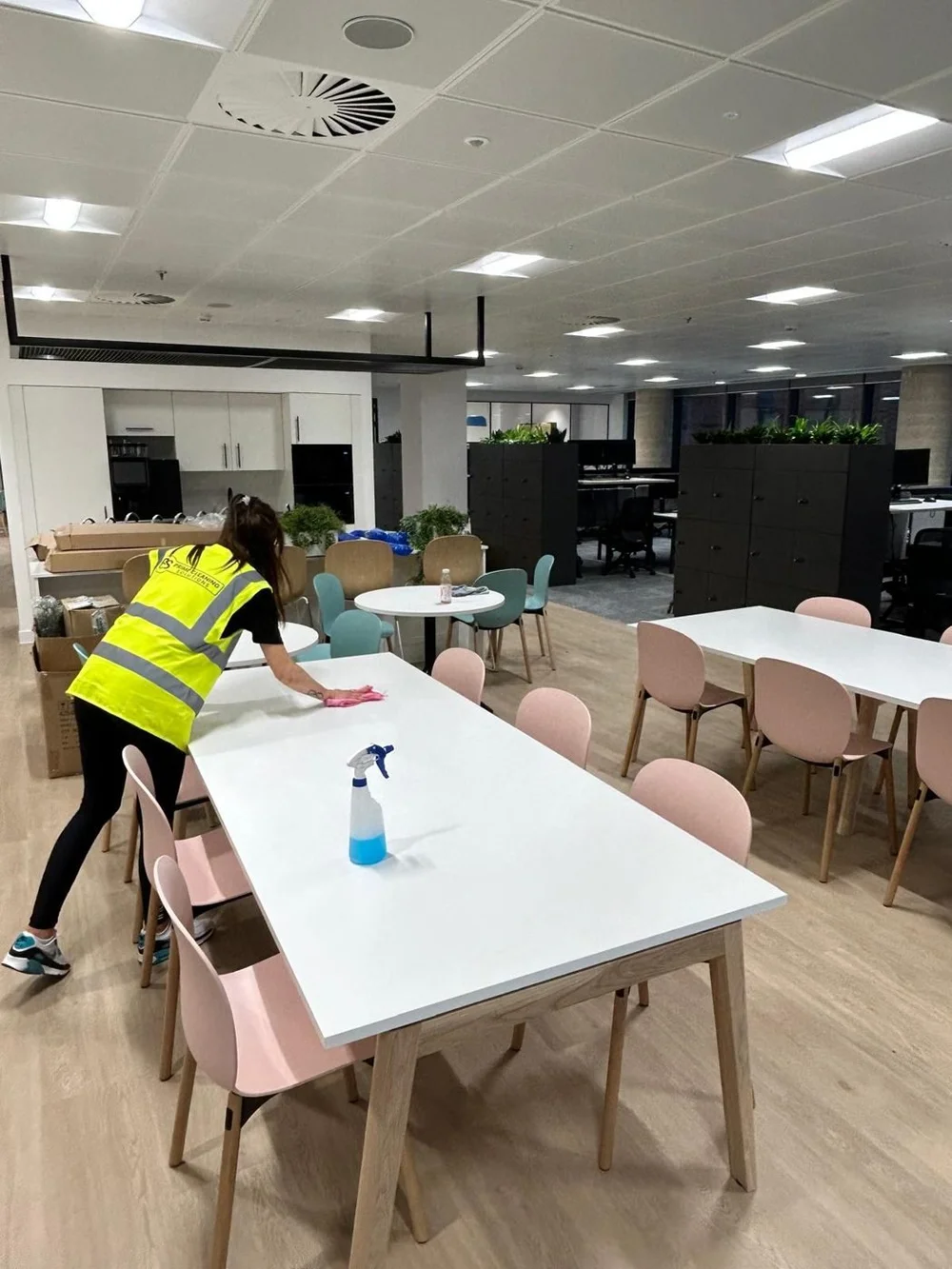 Cleaner wiping tables in a workplace canteen