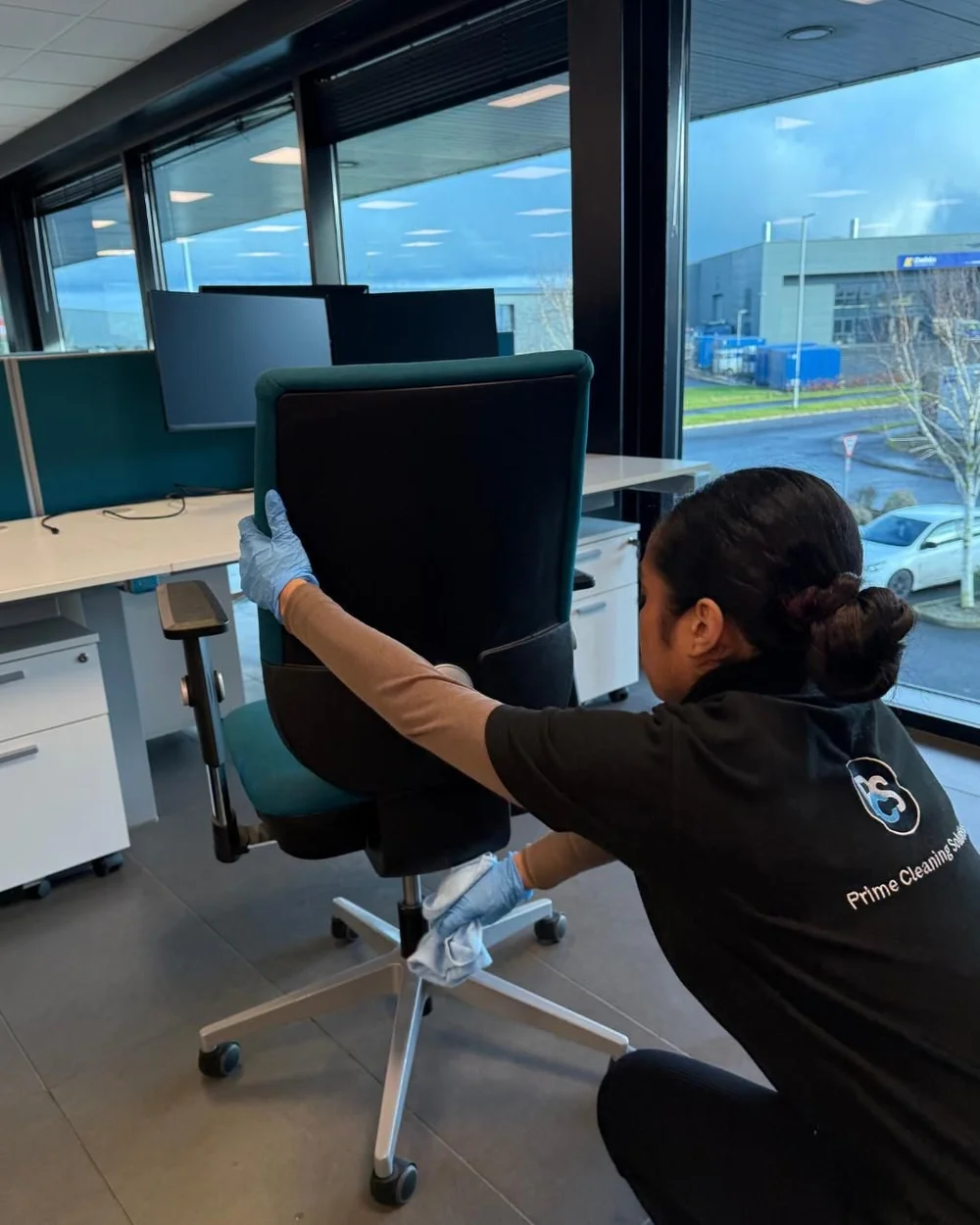 Prime office cleaner wiping down a desk chair in a Belfast office