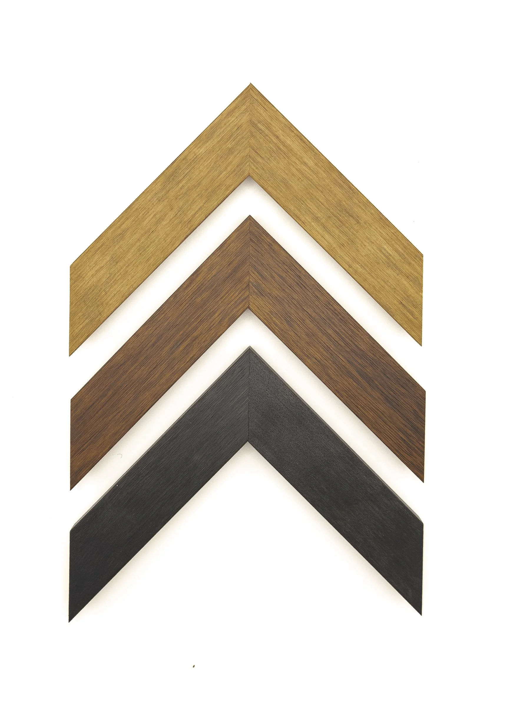 Clean, contemporary picture frame moulding with a wide, flat profile and subtle linear wood-grain texture, shown in golden oak, warm walnut, and deep charcoal finishes. Available for custom framing in Wichita, KS at Dock 410, these versatile moulding