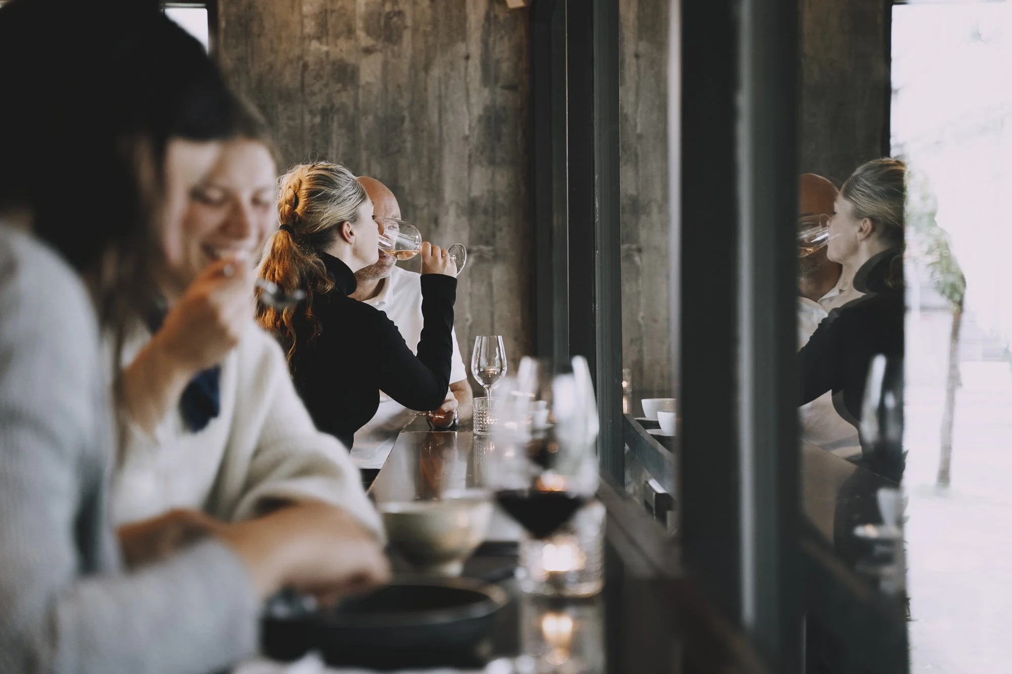 Kafe gjest som drikker vin med refleksjon i vinduet