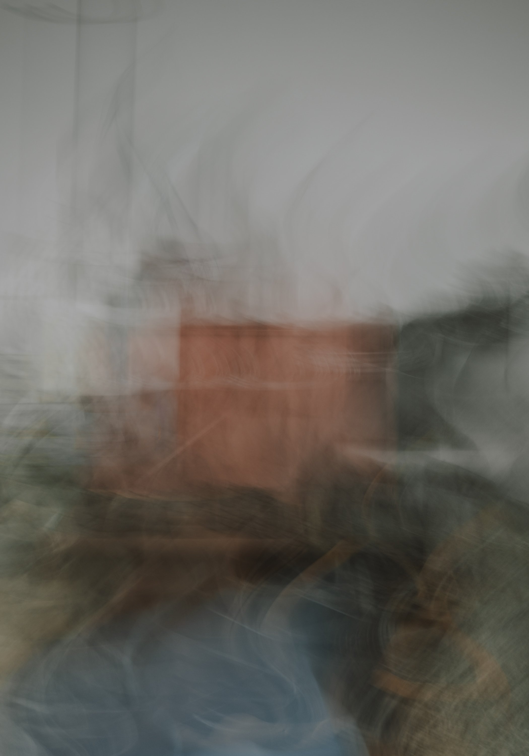 Utydelig bilde av et kvadratisk bord eller benk, med noe ved siden av, i et rom med hvite vegger.