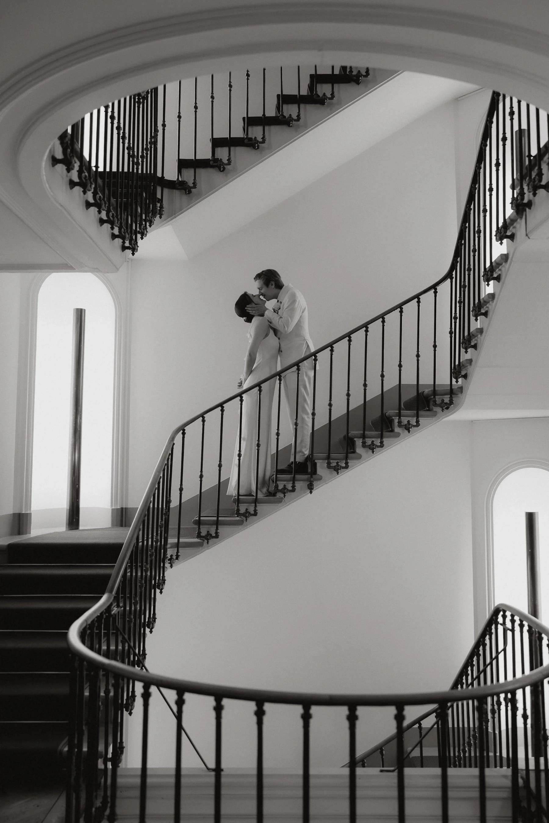 Ein schwarzer und weißer schwarz-weißer Hochzeitspaar auf einer Wendeltreppe in einem hellen Raum.