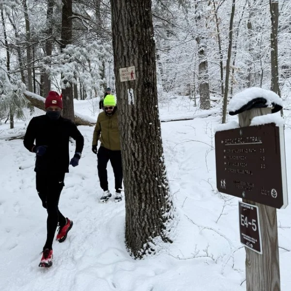 A group of multiethnic trail runners along a snowy forest path.