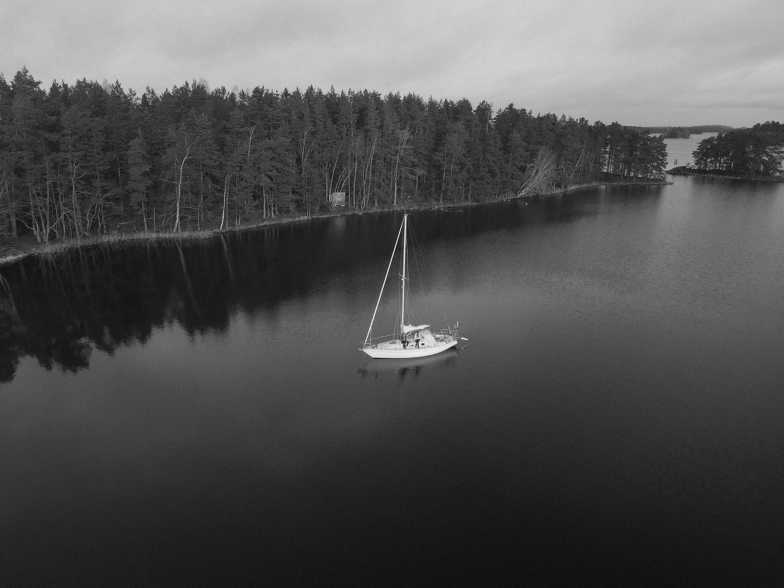couple sitting on a sailboat anchored in the middle of a bay