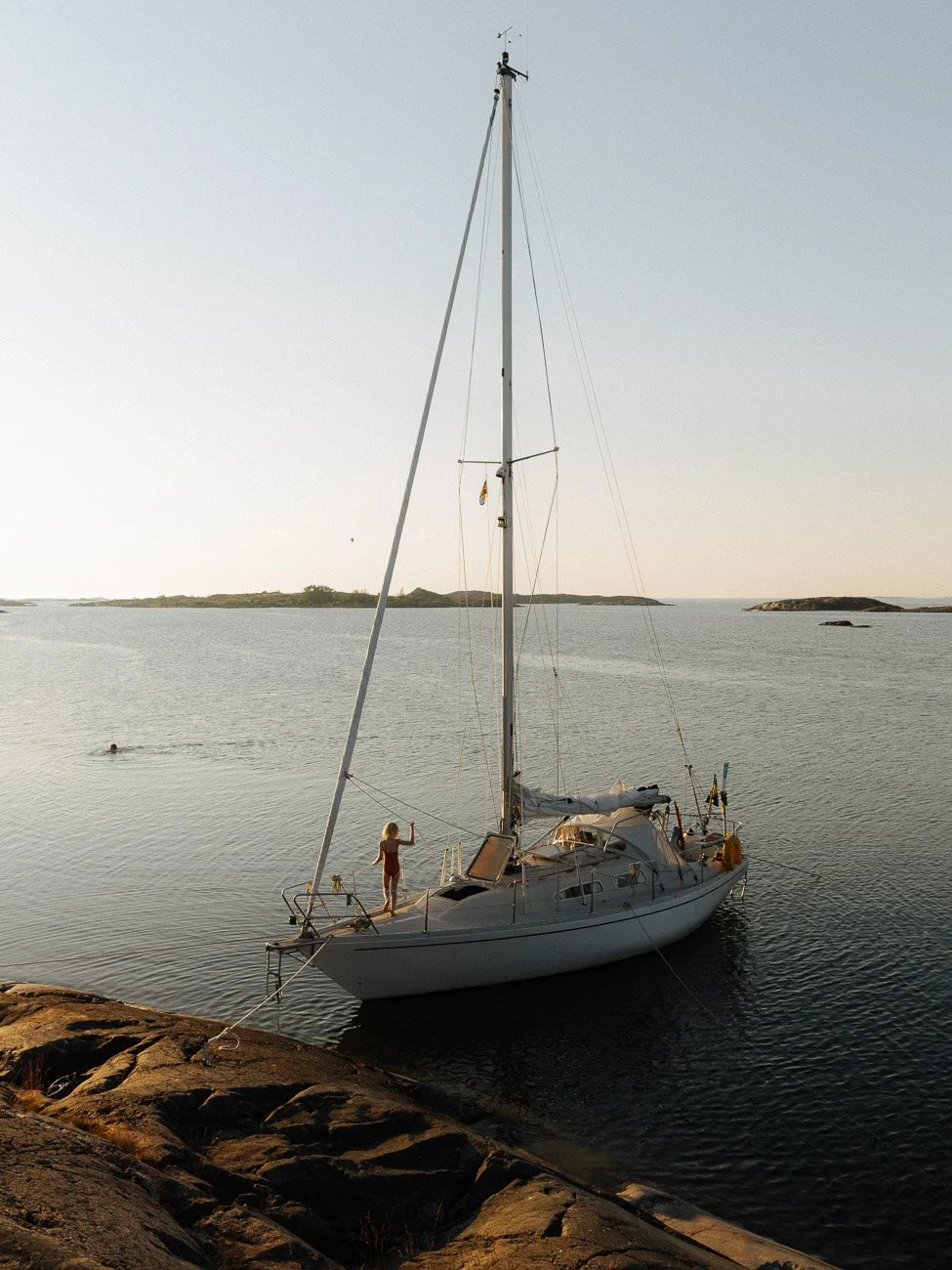 girl standing on a sailboat anchored on an island in the archipelago in the Baltic Sea