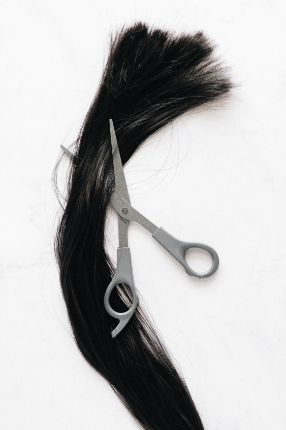 long dark hair with a pair of scissors