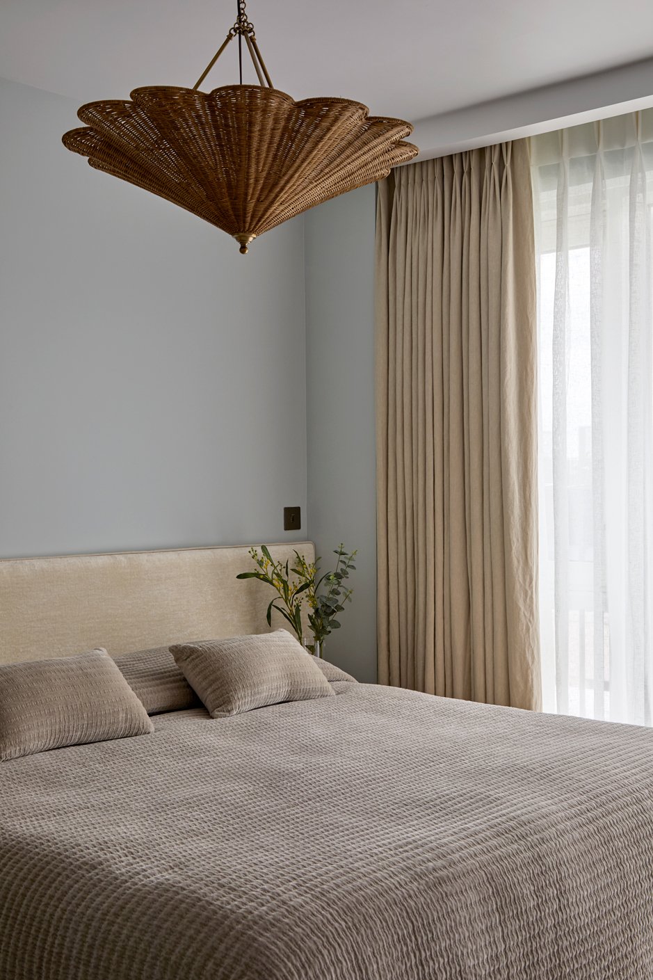 Guest bedroom with bespoke upholstered headboard and wall lighting above the bed.