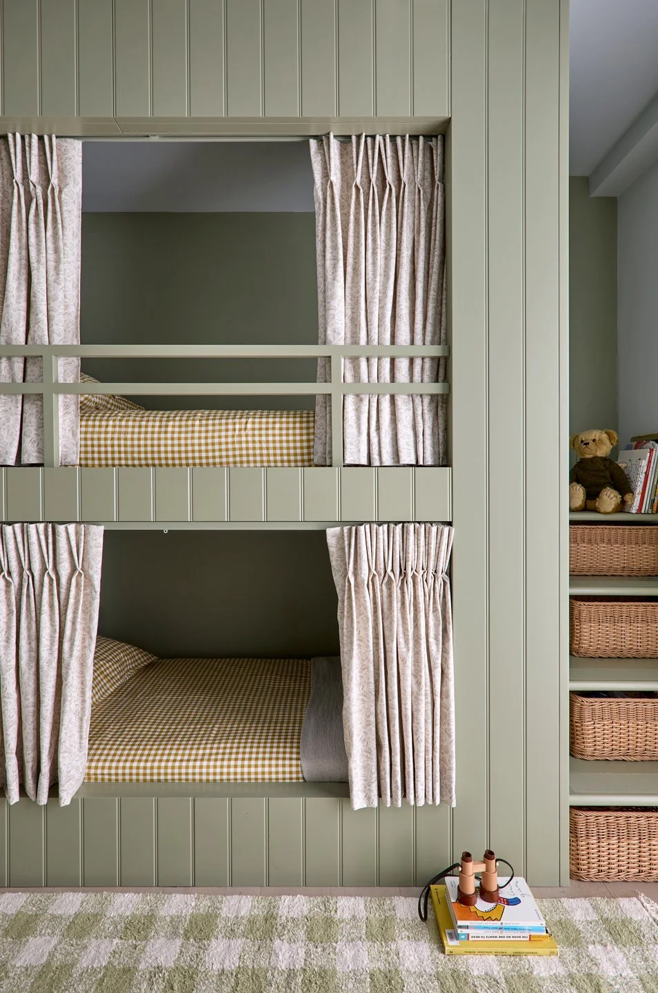 Front view of bespoke panelled bunk beds with curtains and a checked rug in a boys’ bedroom.