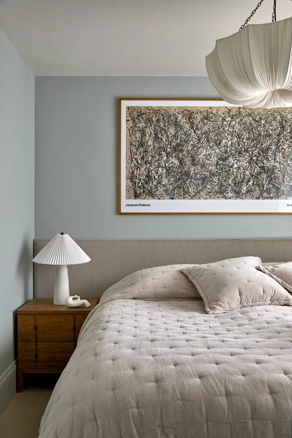 Primary bedroom with bespoke upholstered headboard, bedside lighting and artwork above the bed.
