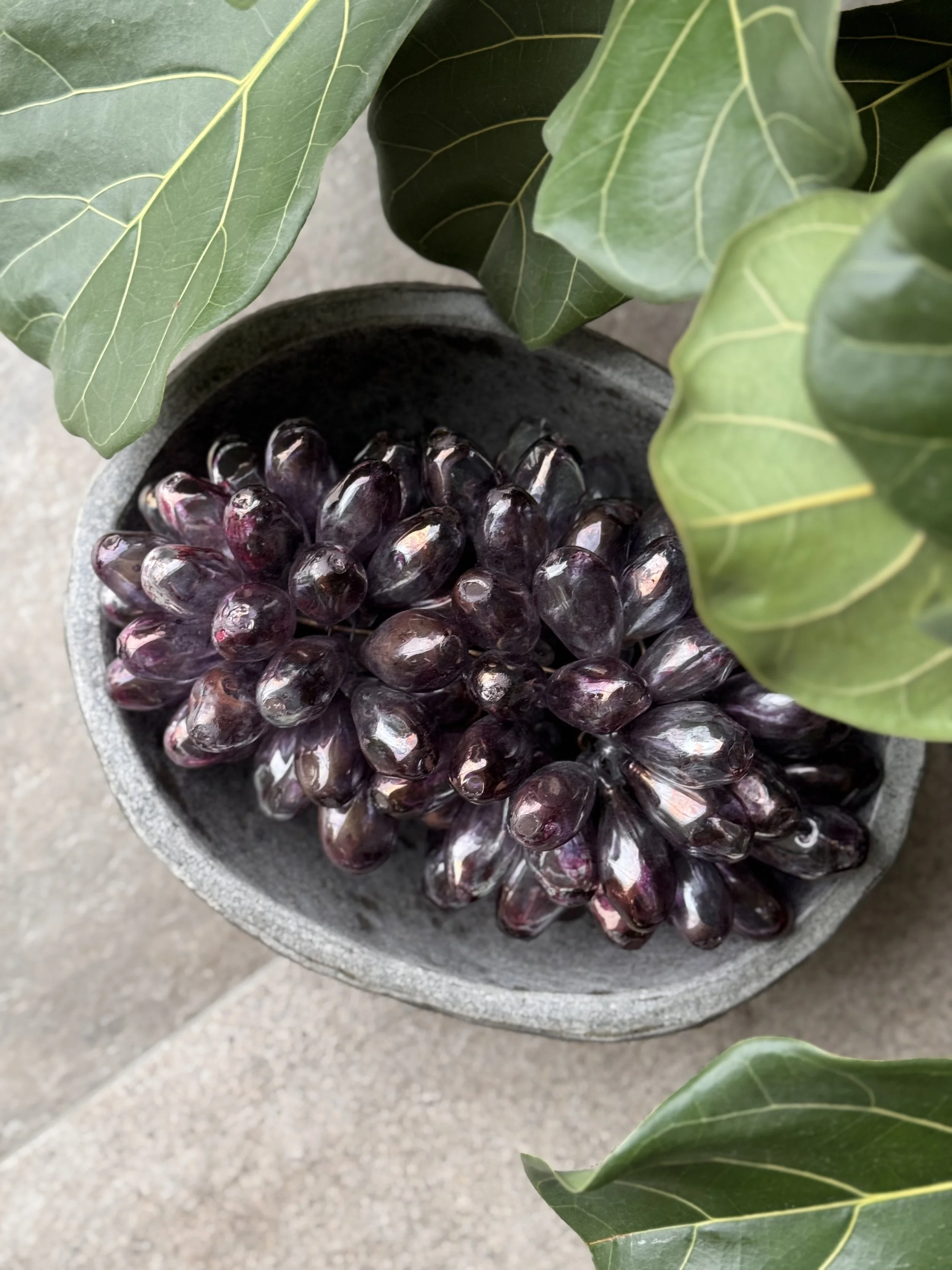 Glass grapes in stone bowl