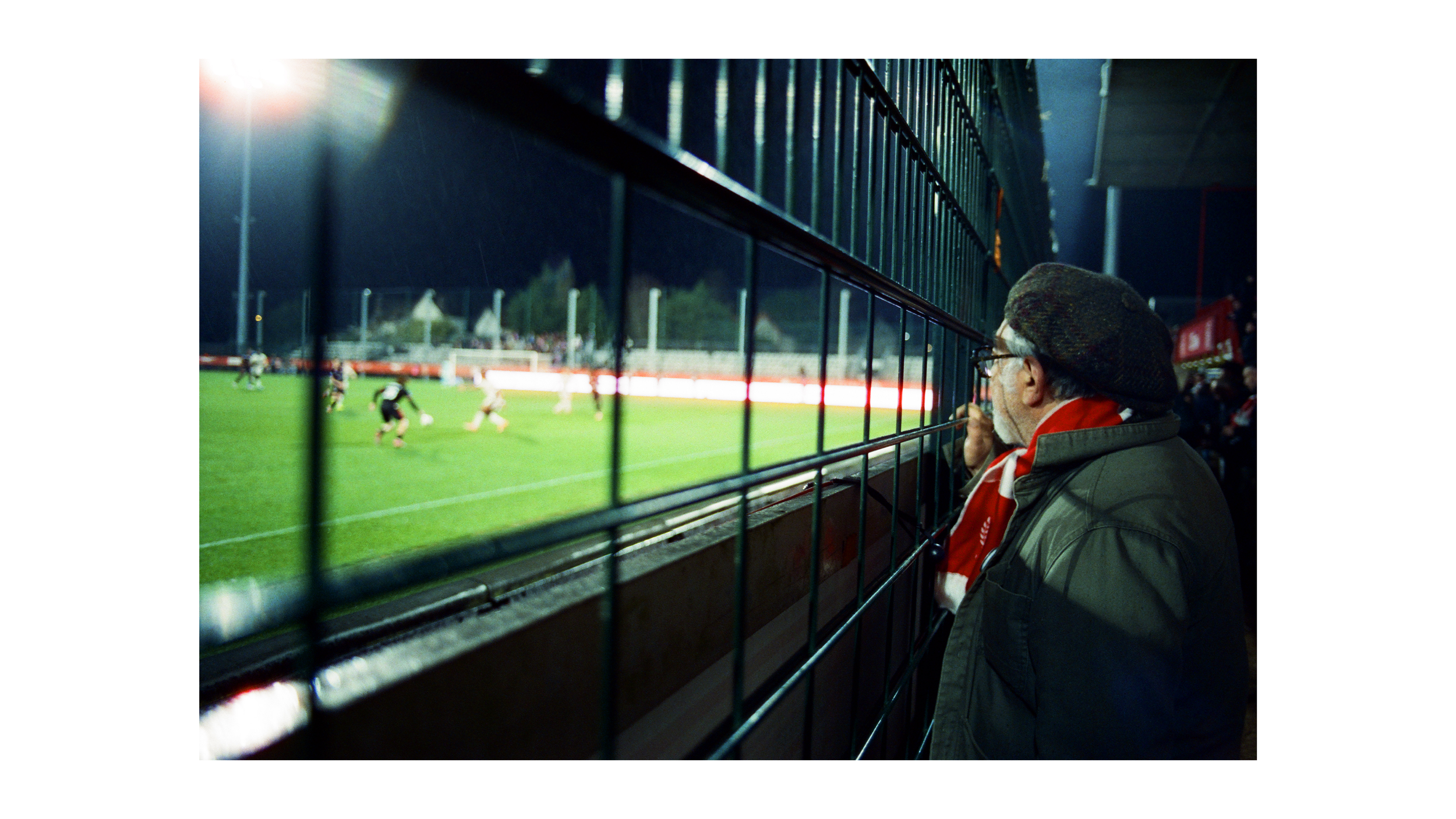 supporter qui regarde le match entre les grilles.png