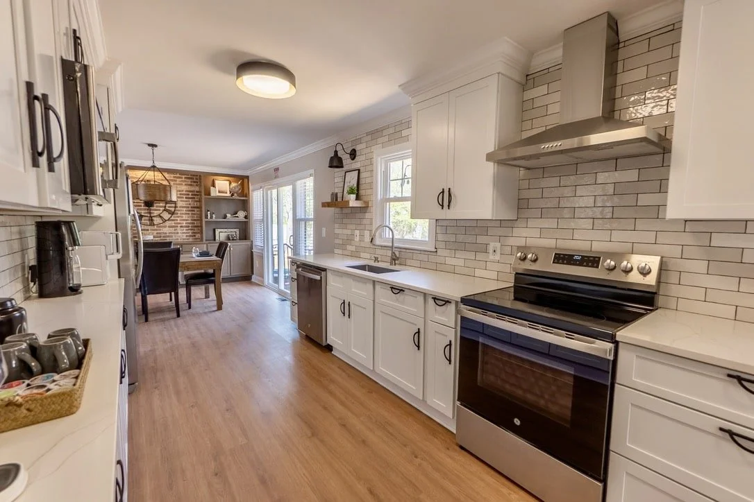 Modern kitchen and dining area with white cabinets, stainless steel appliances, and light wood flooring.