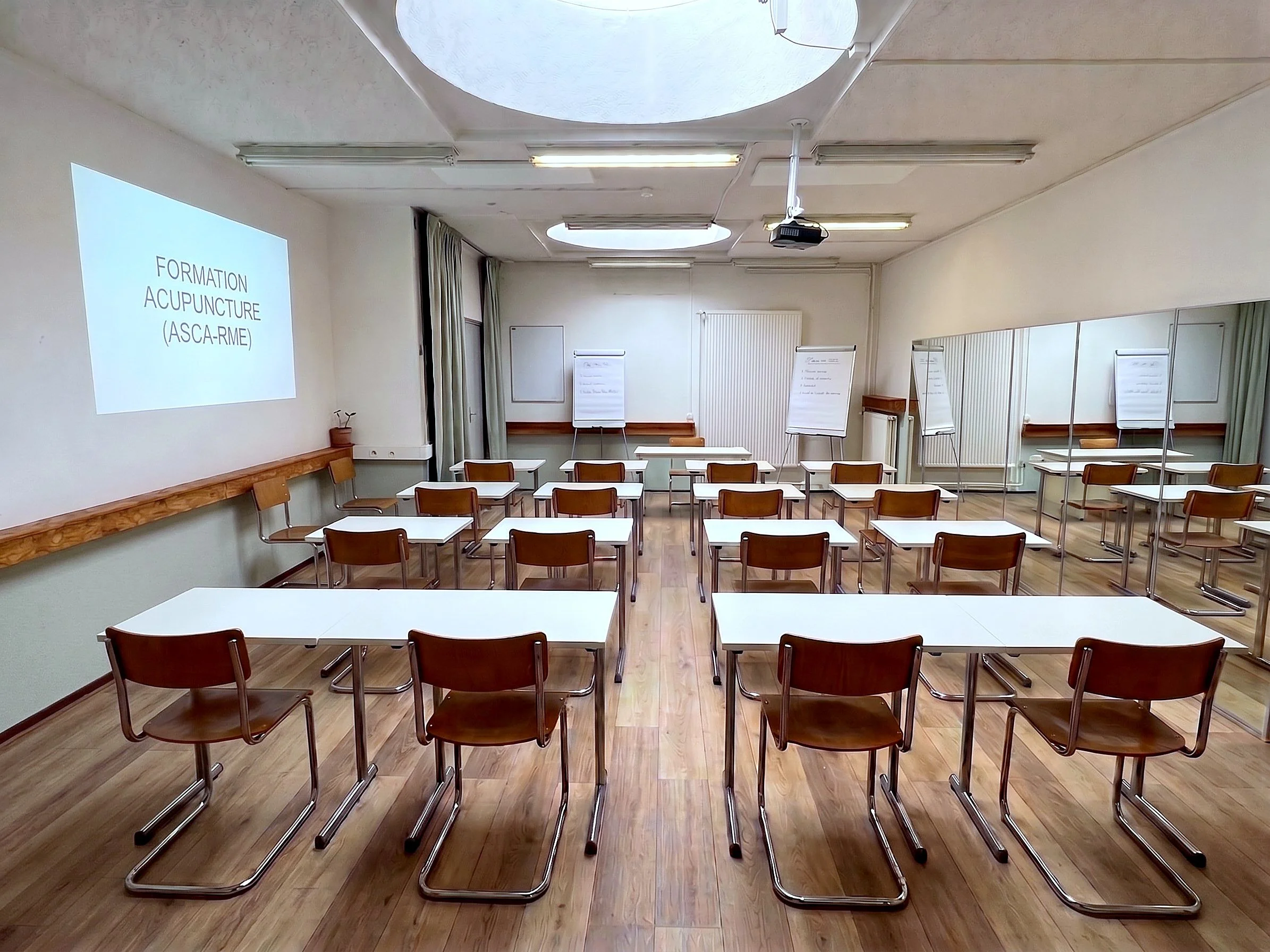 Salle Claudia à Genève en configuration formation, tables et chaises face à l'écran