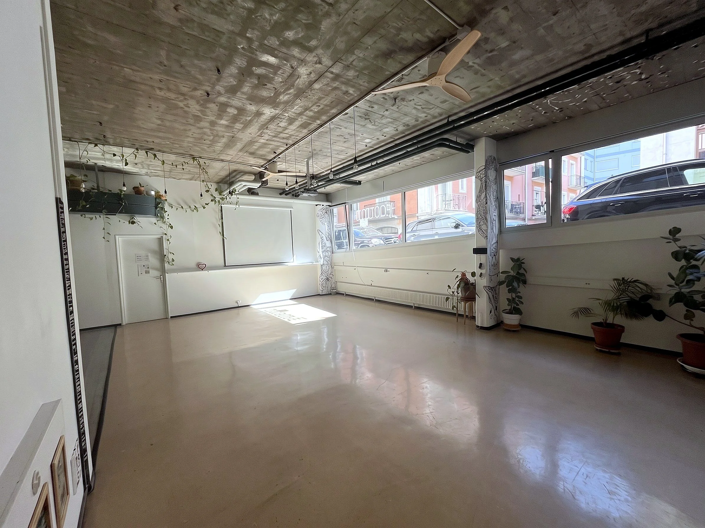 Salle Jean-Mich' de 80 m² vide à louer à Genève, murs blancs et grandes fenêtres