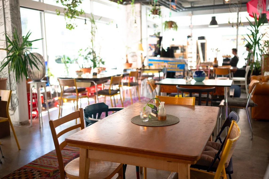 Salle du café-restaurant FOOUND à Genève, tables en bois et plantes