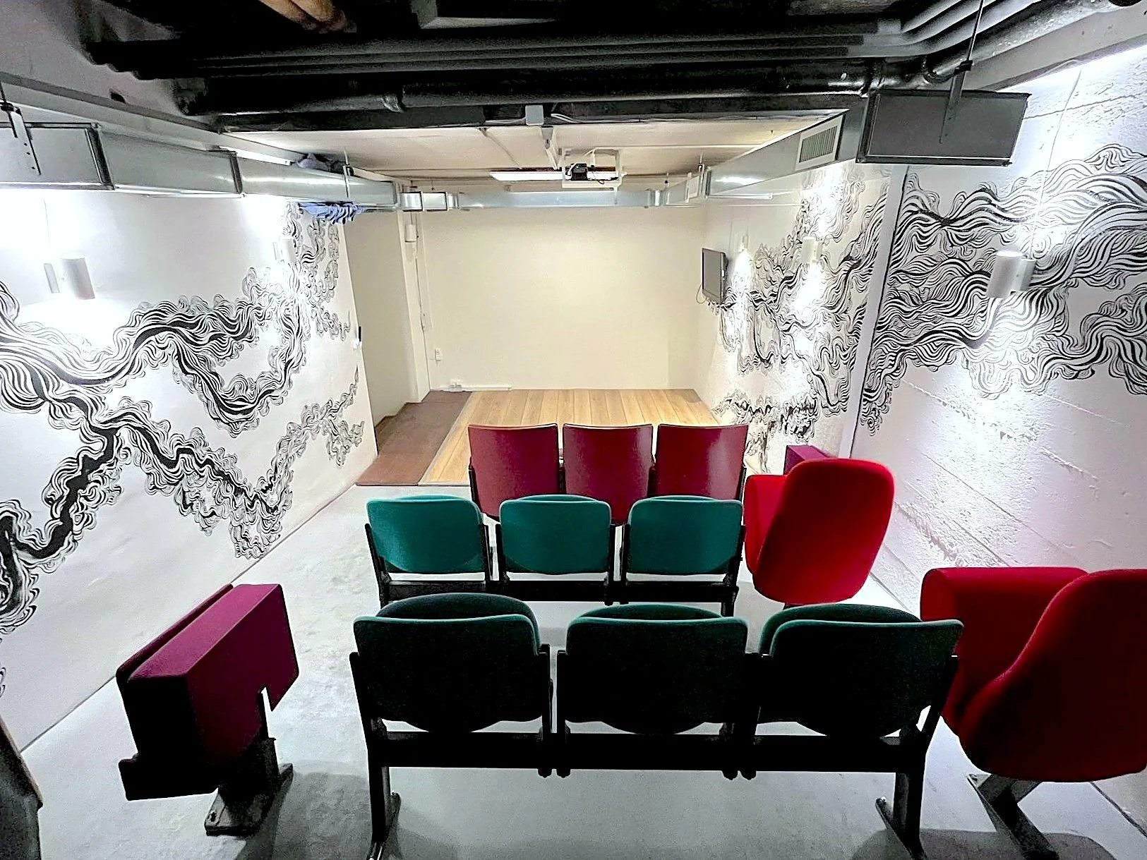 Salle Betty de 30 m² à Genève, auditorium avec 18 sièges de cinéma rétro et fresque murale