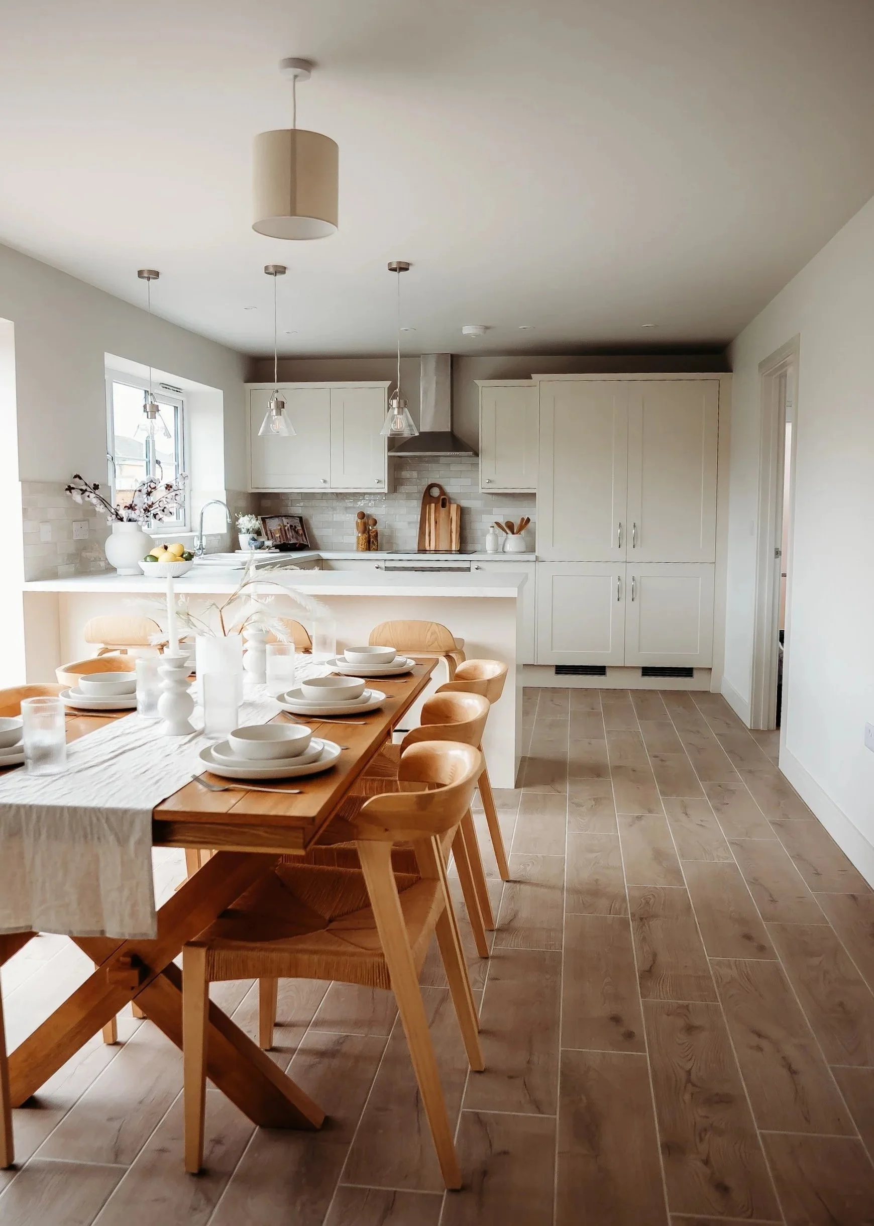 country-kitchen-tile-floor-wood-cross-leg-dining-table-scandi-chairs-rattan-dressed-dinner-setting-staged-house-for-sale.jpg