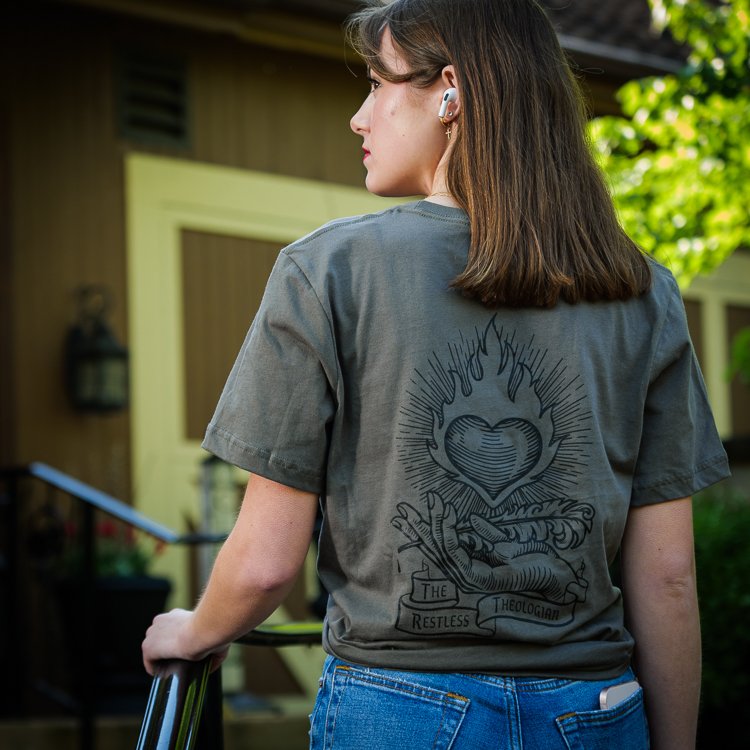 Close-up of The Restless Theologian logo on green t-shirt, showcasing design inspired by Augustine.