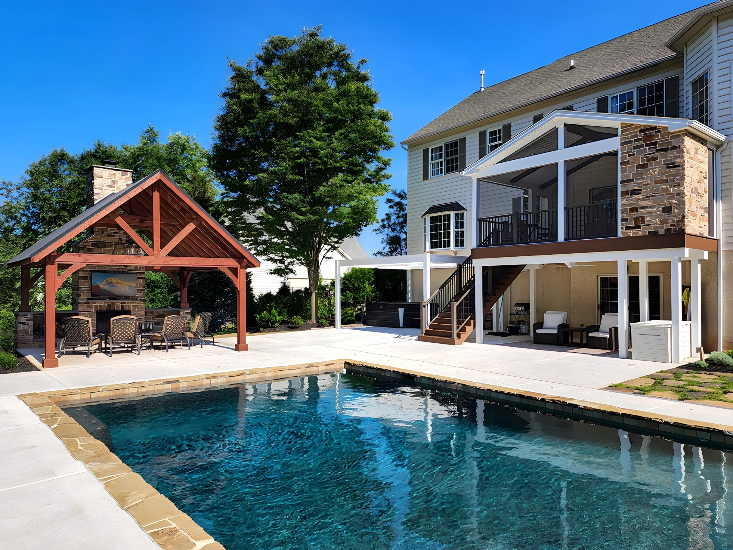 Backyard with swimming pool, patio furniture, a covered outdoor seating area, and a multi-story house with a screened-in porch and stone accents.