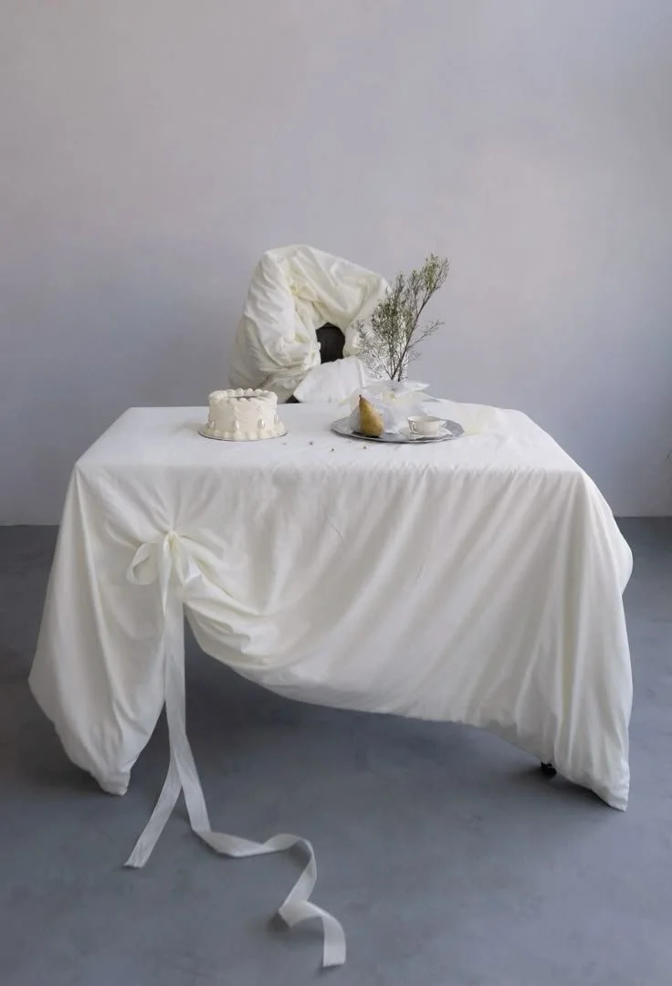 A draped white tablescape styled with delicate objects