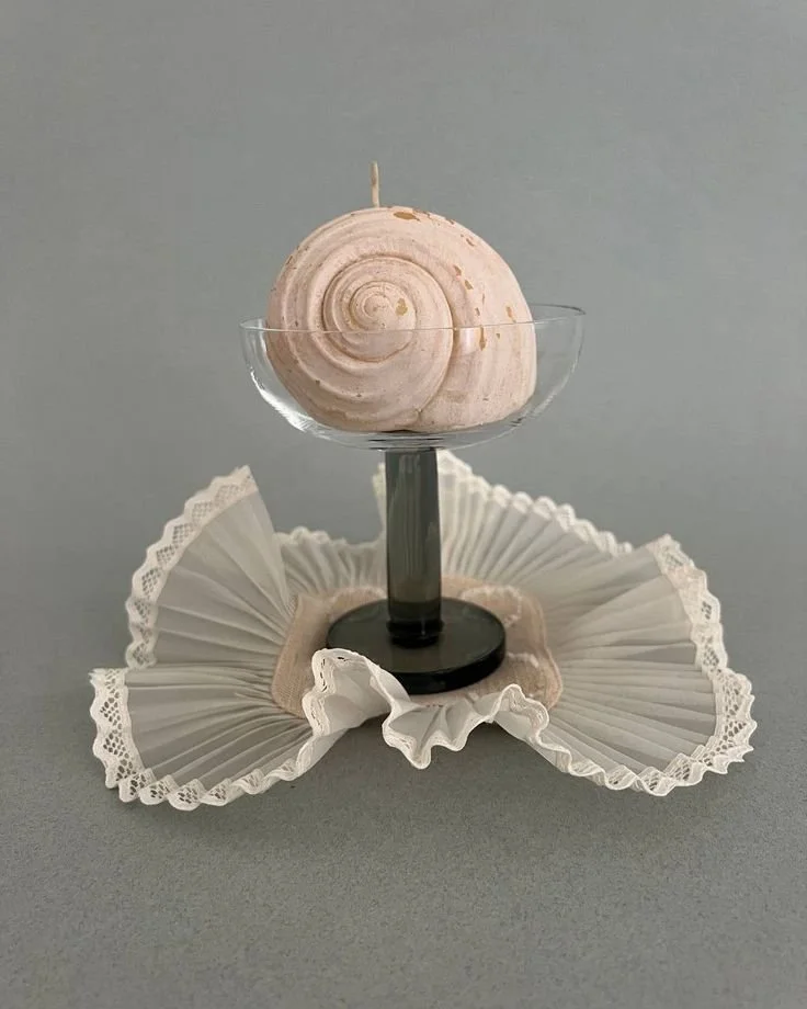 A sculptural pale form on a slender stand
