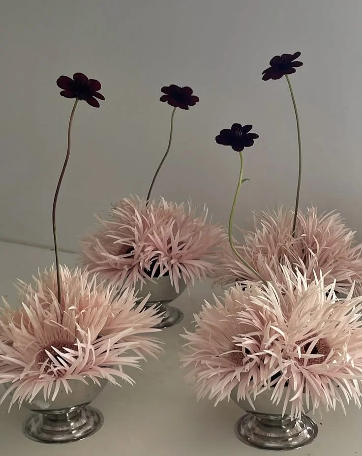Pale pink floral arrangements in silver vessels
