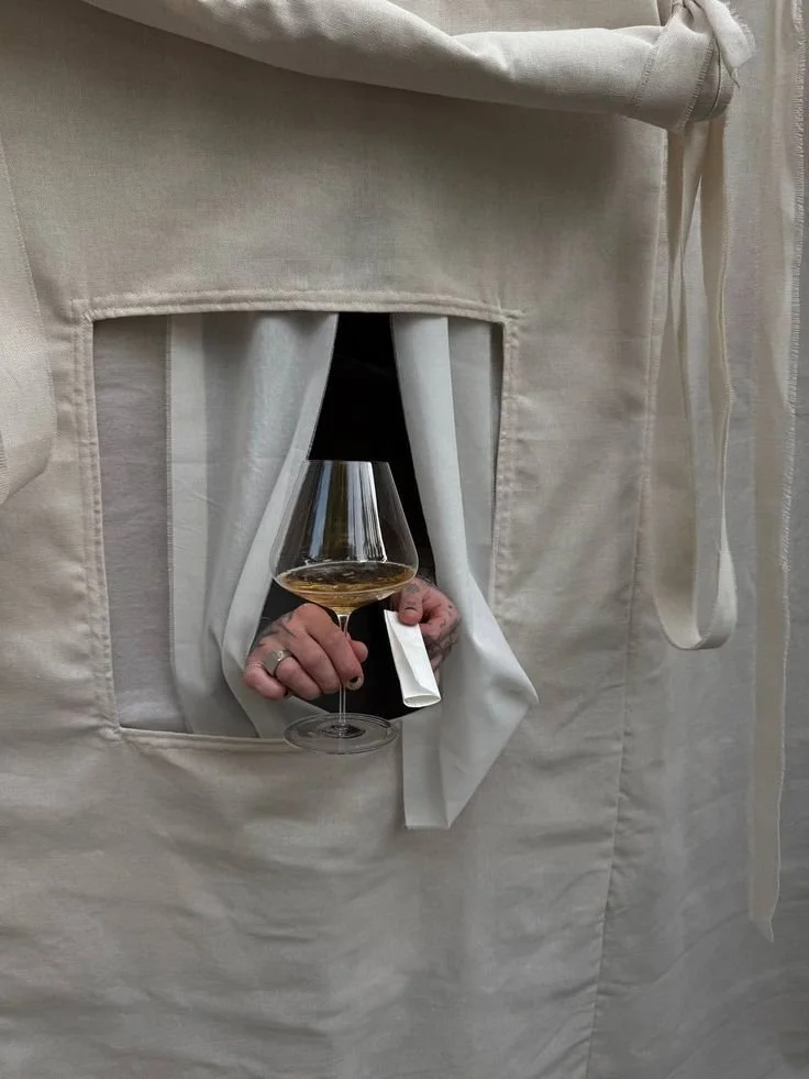 A hand holding a glass through soft white fabric