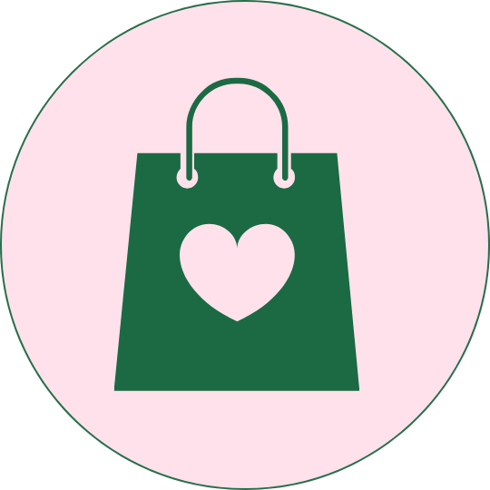 Green shopping bag with a heart on it, set against a pink circular background.