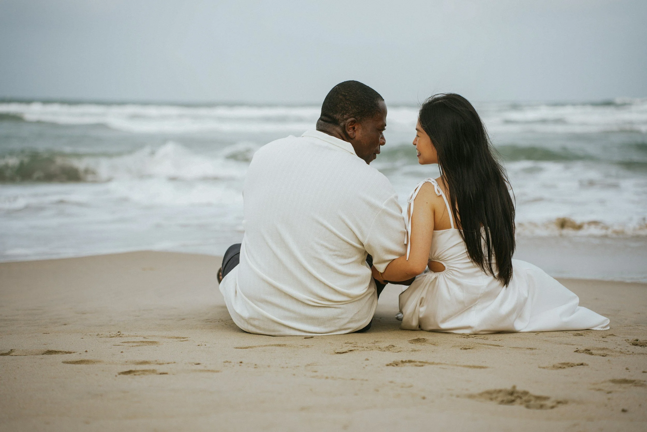 interracial couple on the beach gazing in each others eyes