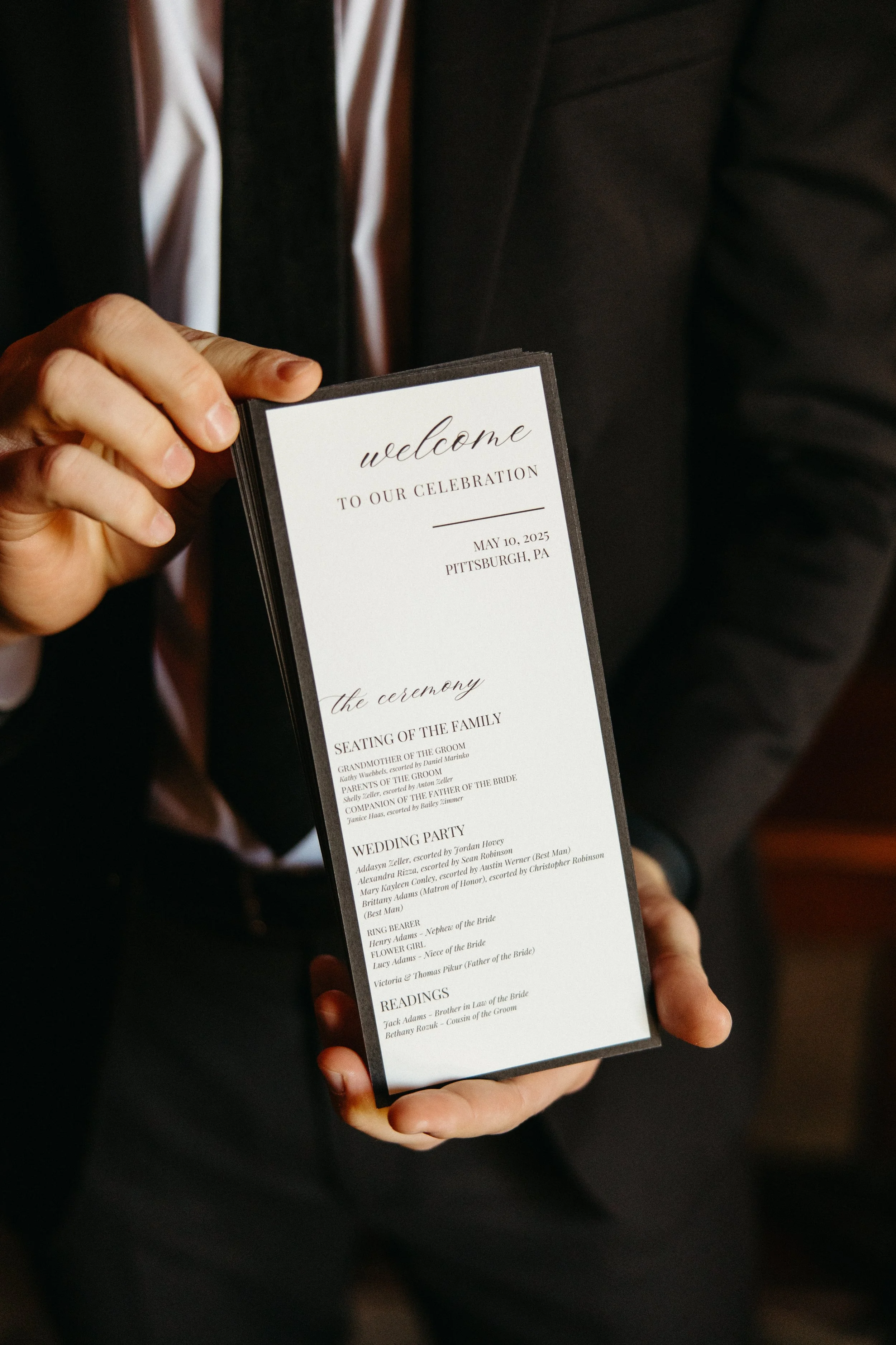 Close-up of a wedding place card labeled "Bride" on white paper with elegant script, next to a dried orange slice garnished with a ribbon.